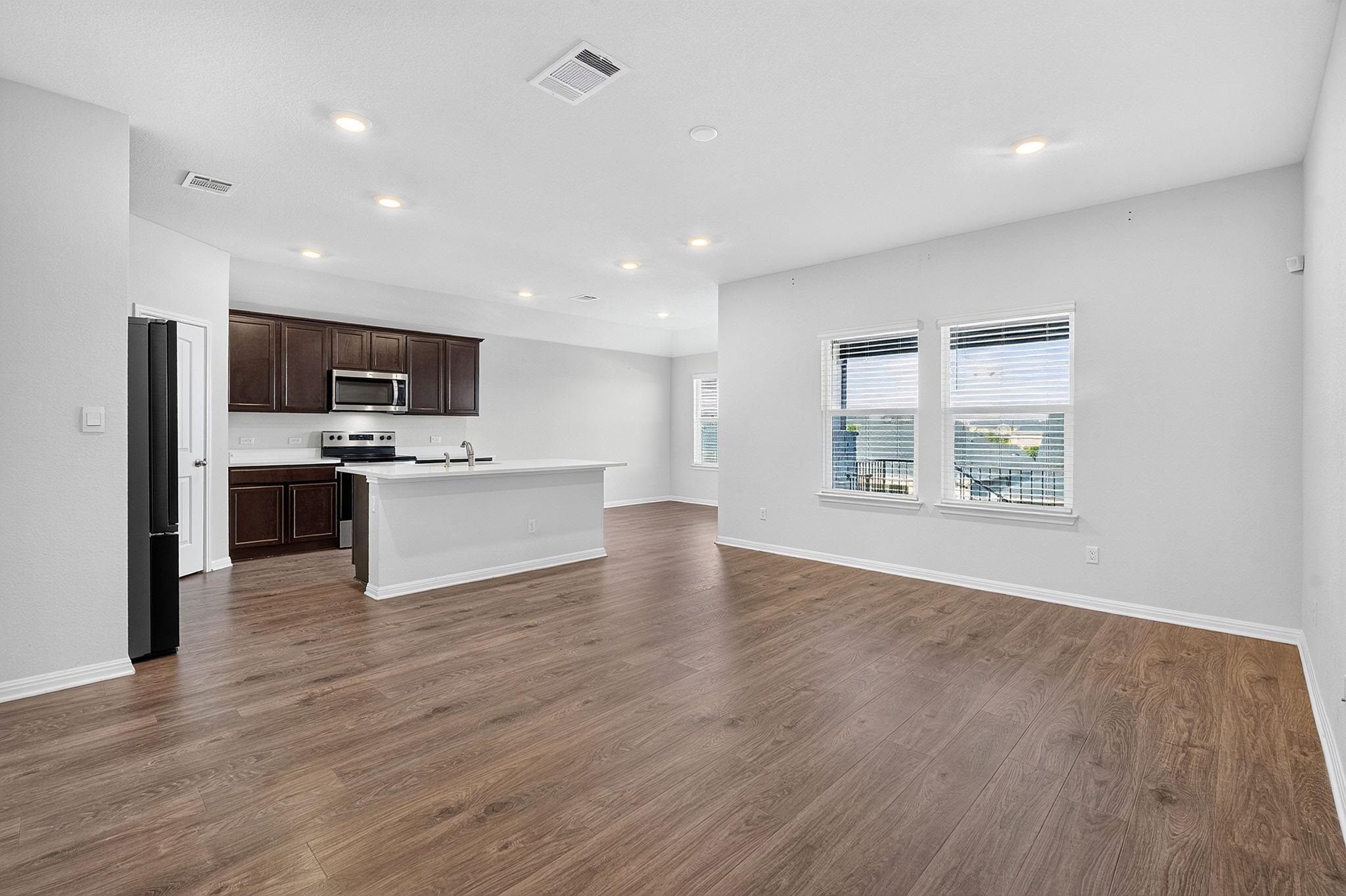 An airy open layout connects the living space to a modern kitchen with rich wood tones.