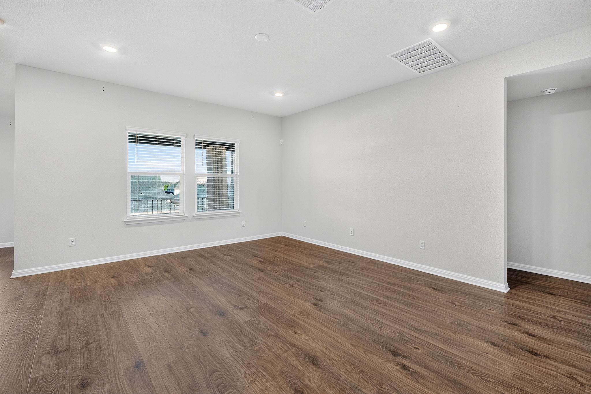 Rich wood-textured flooring contrasts with crisp white walls and modern recessed lighting.