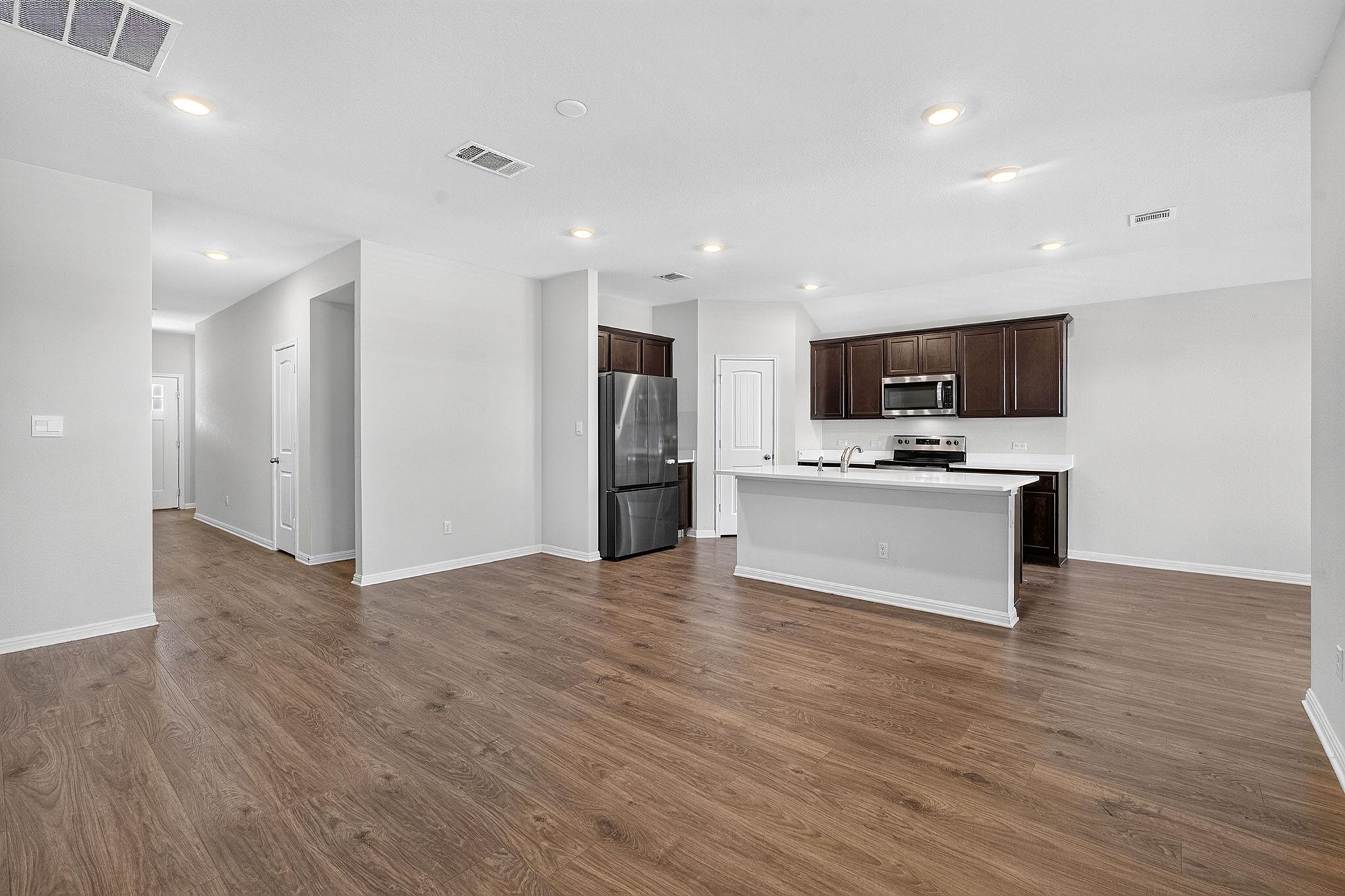Rich wood flooring anchors this open-concept layout leading directly into a modern kitchen design.