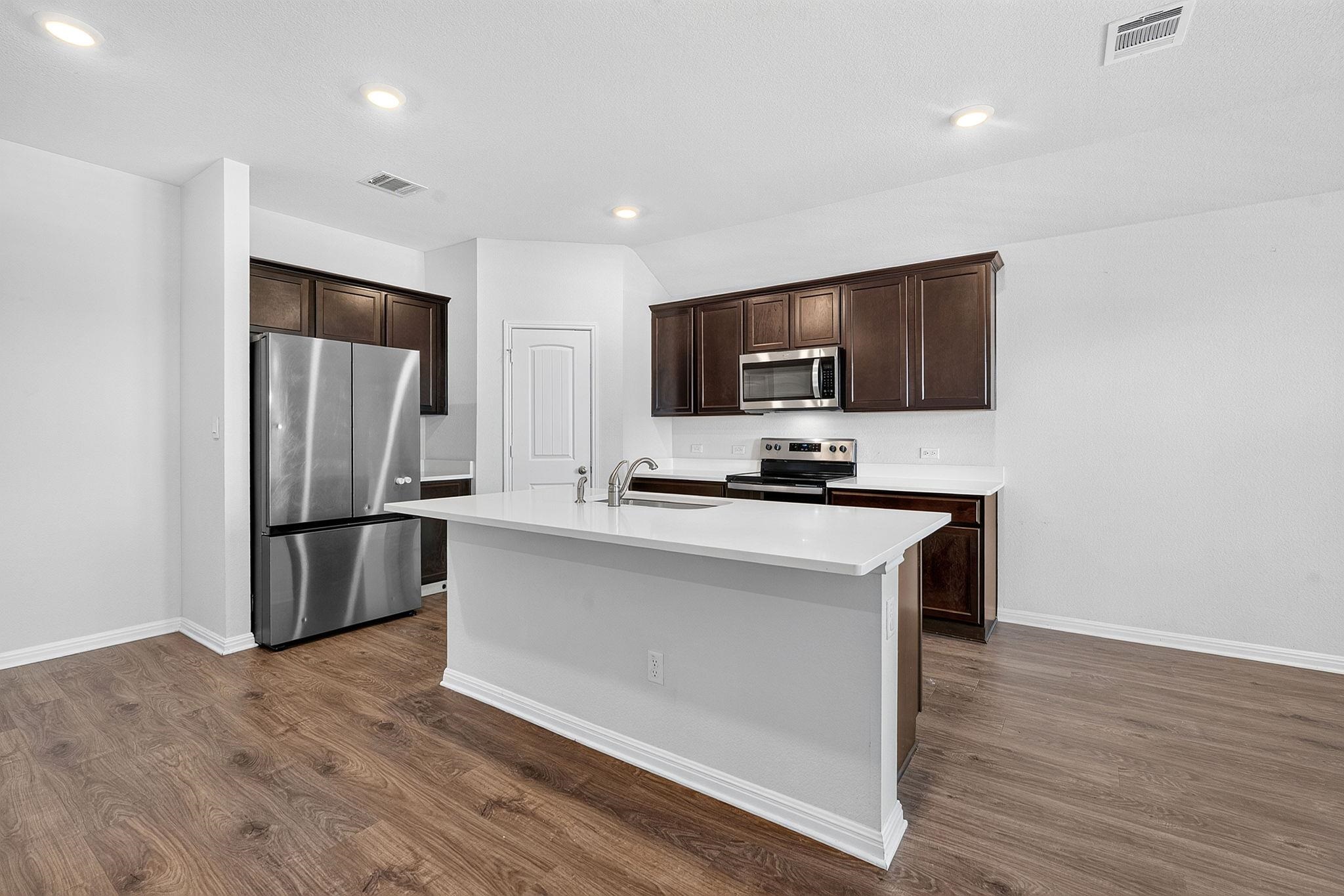 Gleaming wood floors anchor a culinary space defined by dark cabinetry and clean countertops.