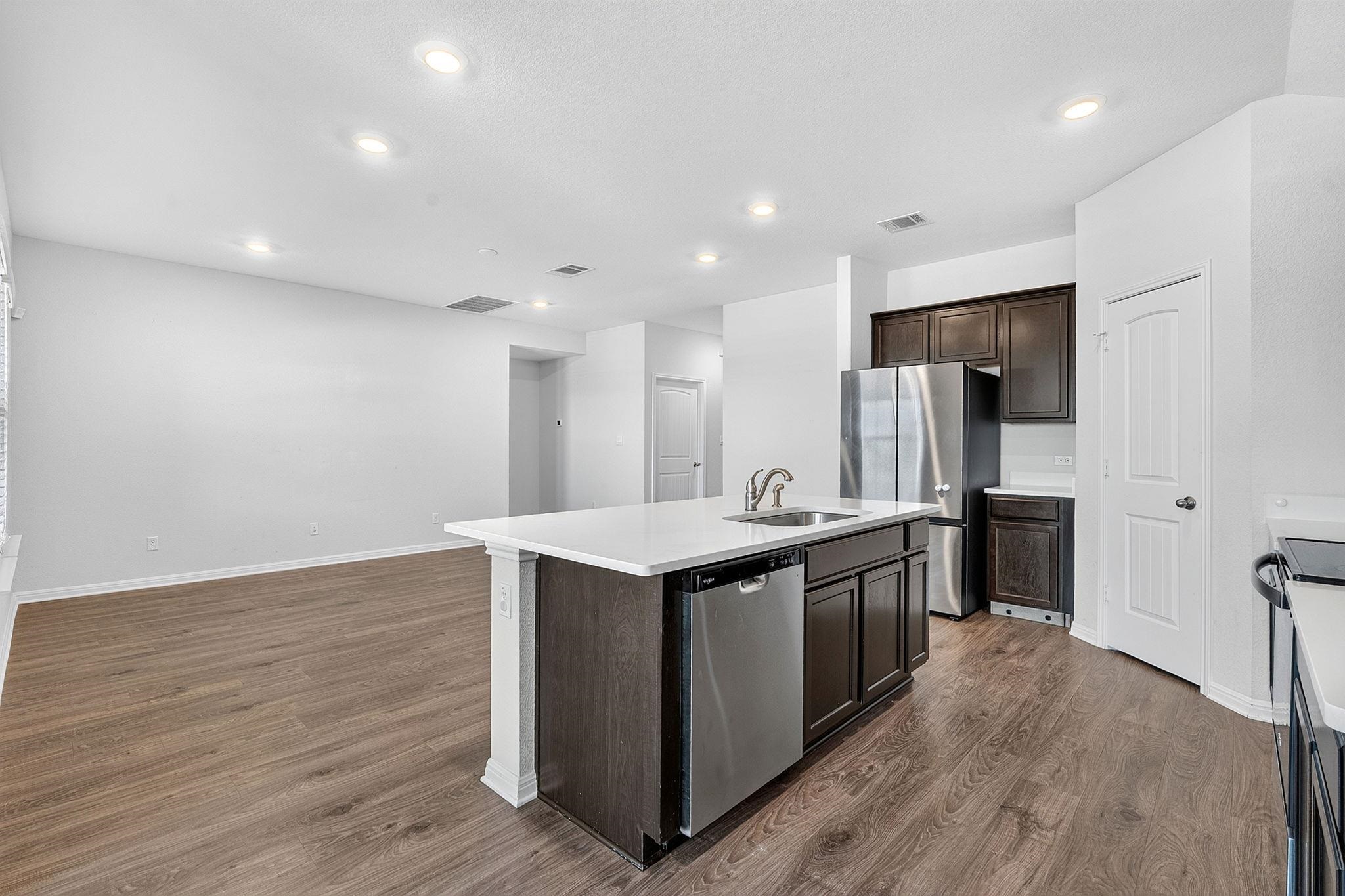 An open kitchen anchors the main level, featuring a stone-topped island and recessed lighting.