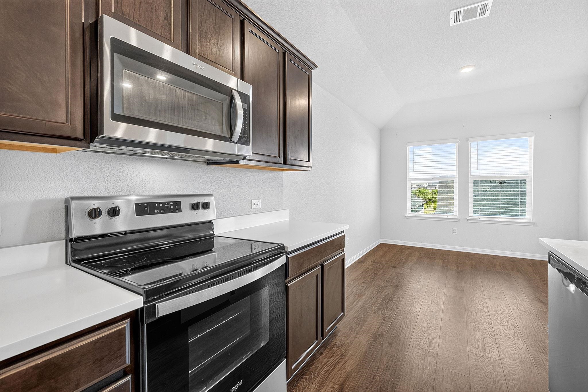 Rich dark wood cabinetry contrasts with sleek solid surface countertops and stainless appliances.