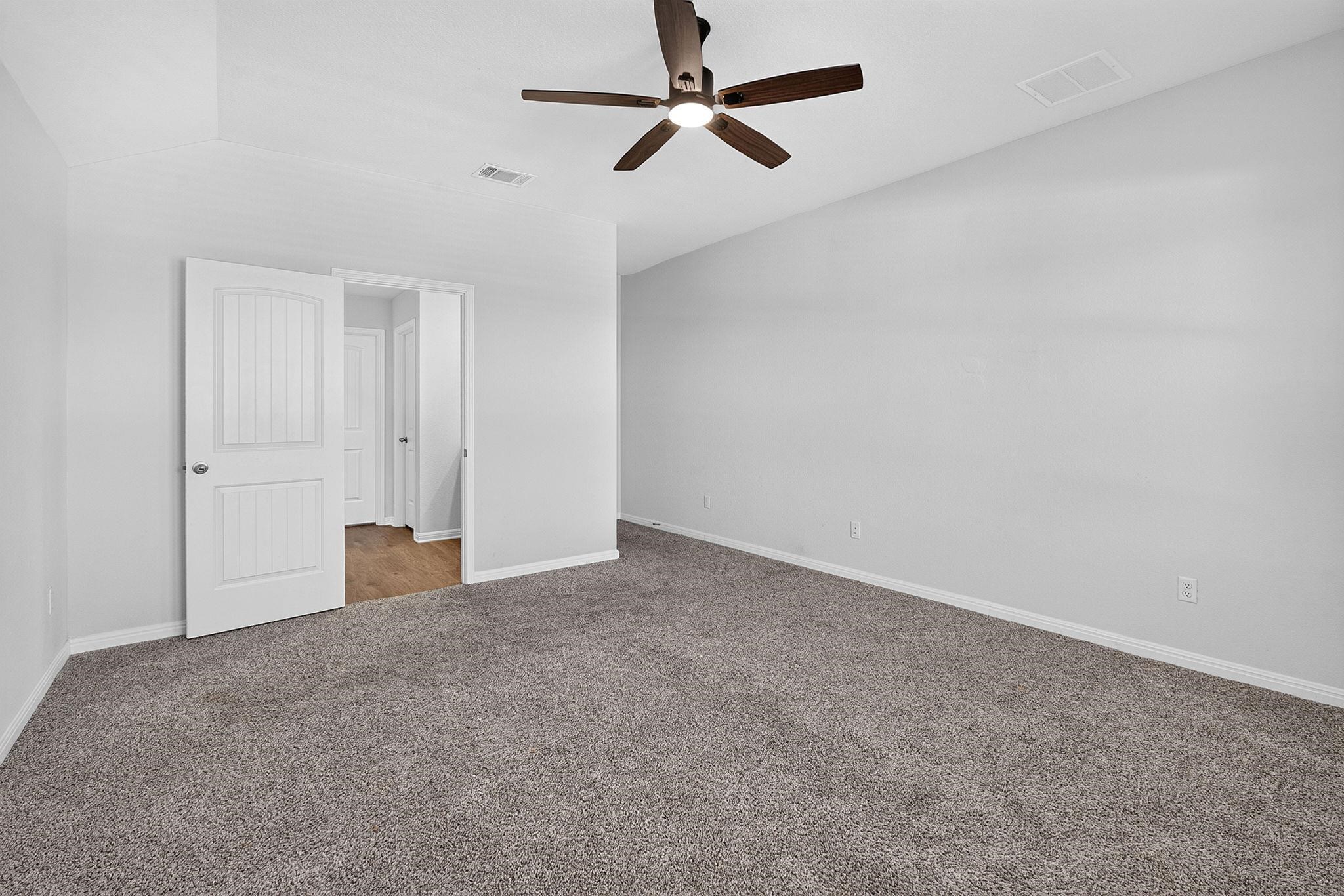 Vaulted ceilings and plush carpeting define this airy bedroom space.
