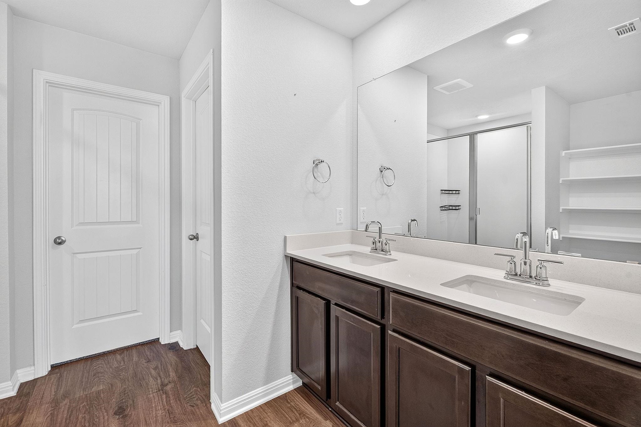 Dark cabinetry contrasts beautifully with clean countertops and a large mirror in this bathroom.