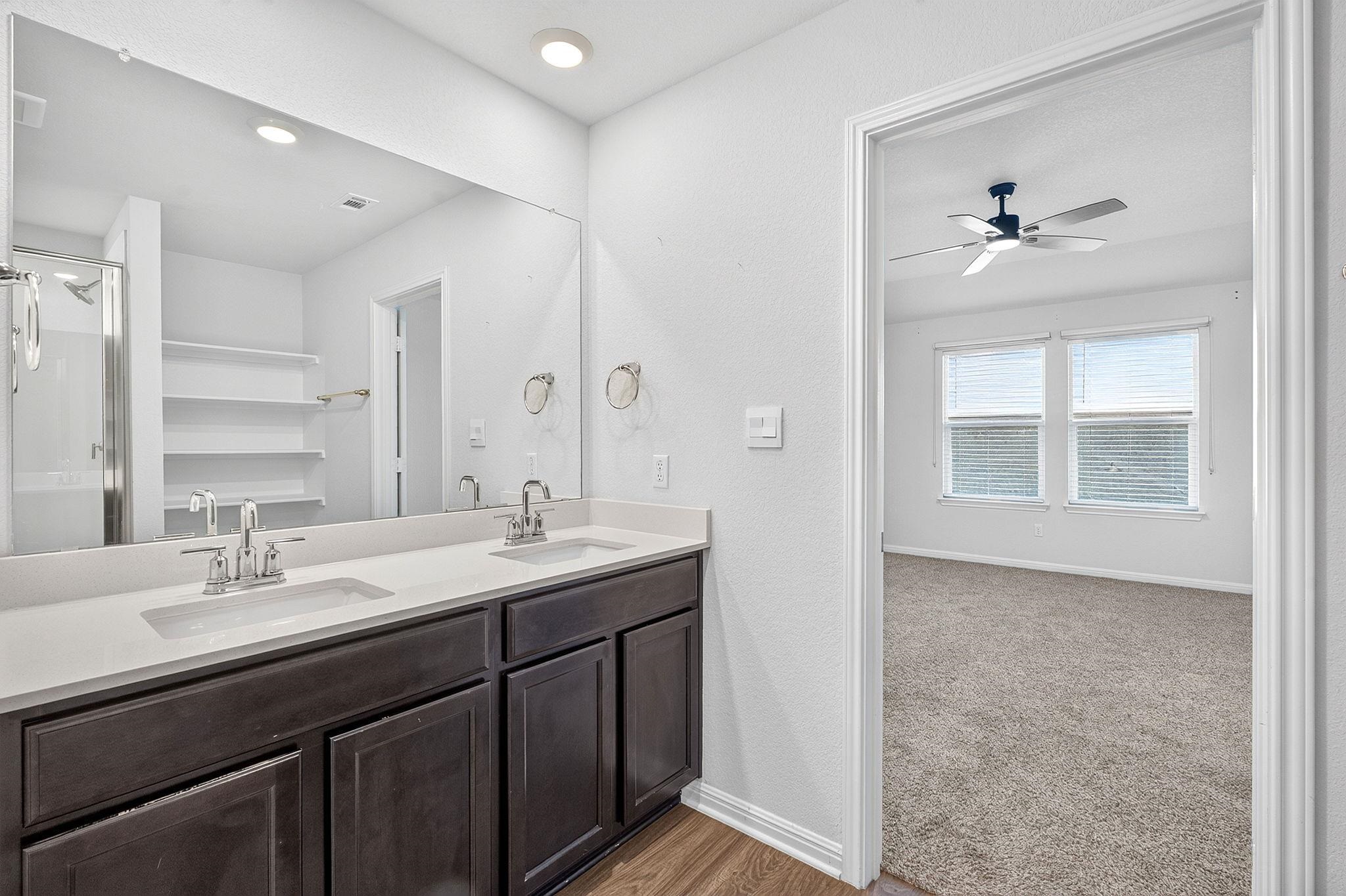 Clean lines and a double vanity define this functional bathroom adjoining a carpeted bedroom suite.