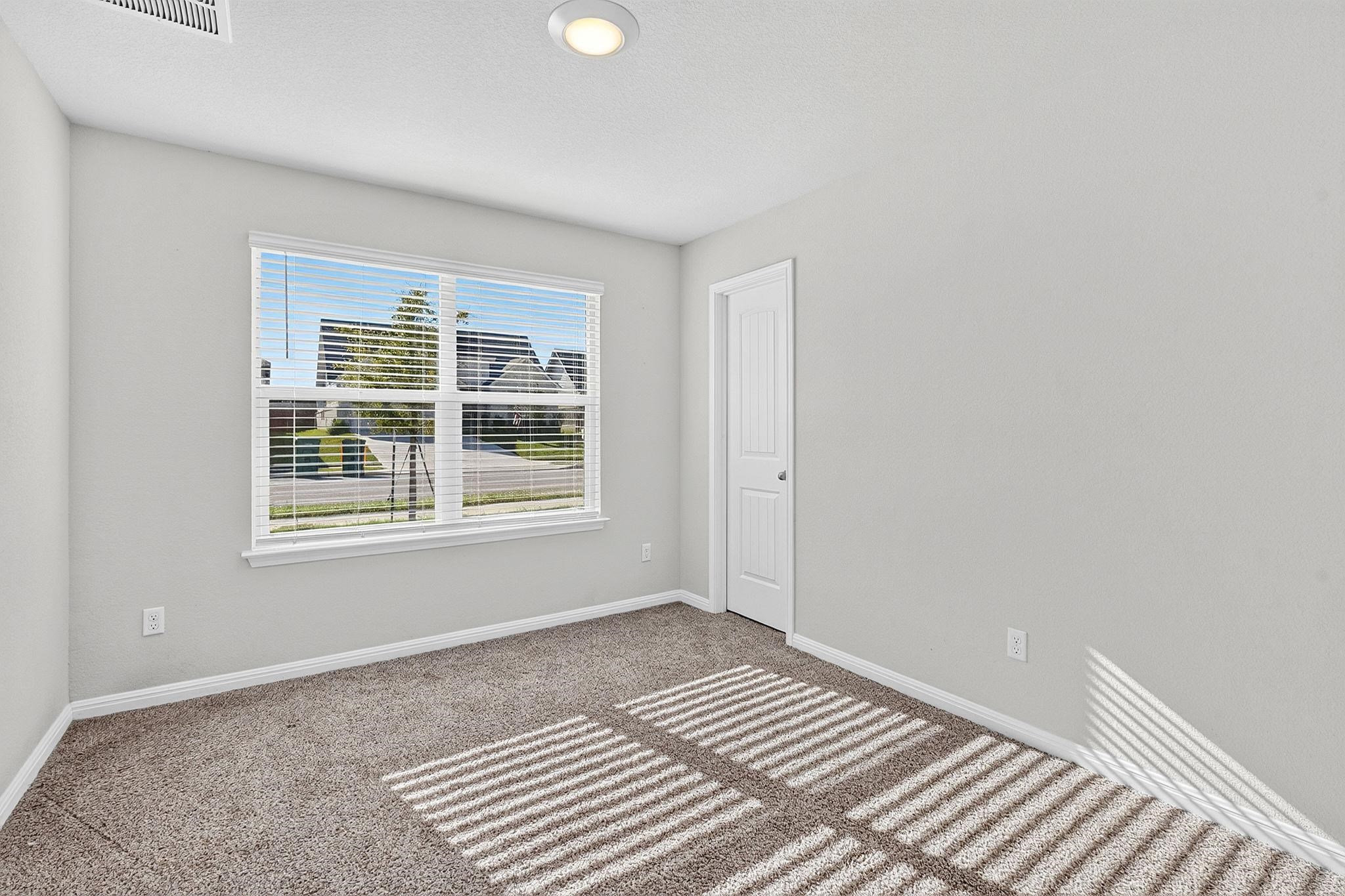 Soft plush carpeting paired with clean neutral walls anchors this versatile bedroom space.
