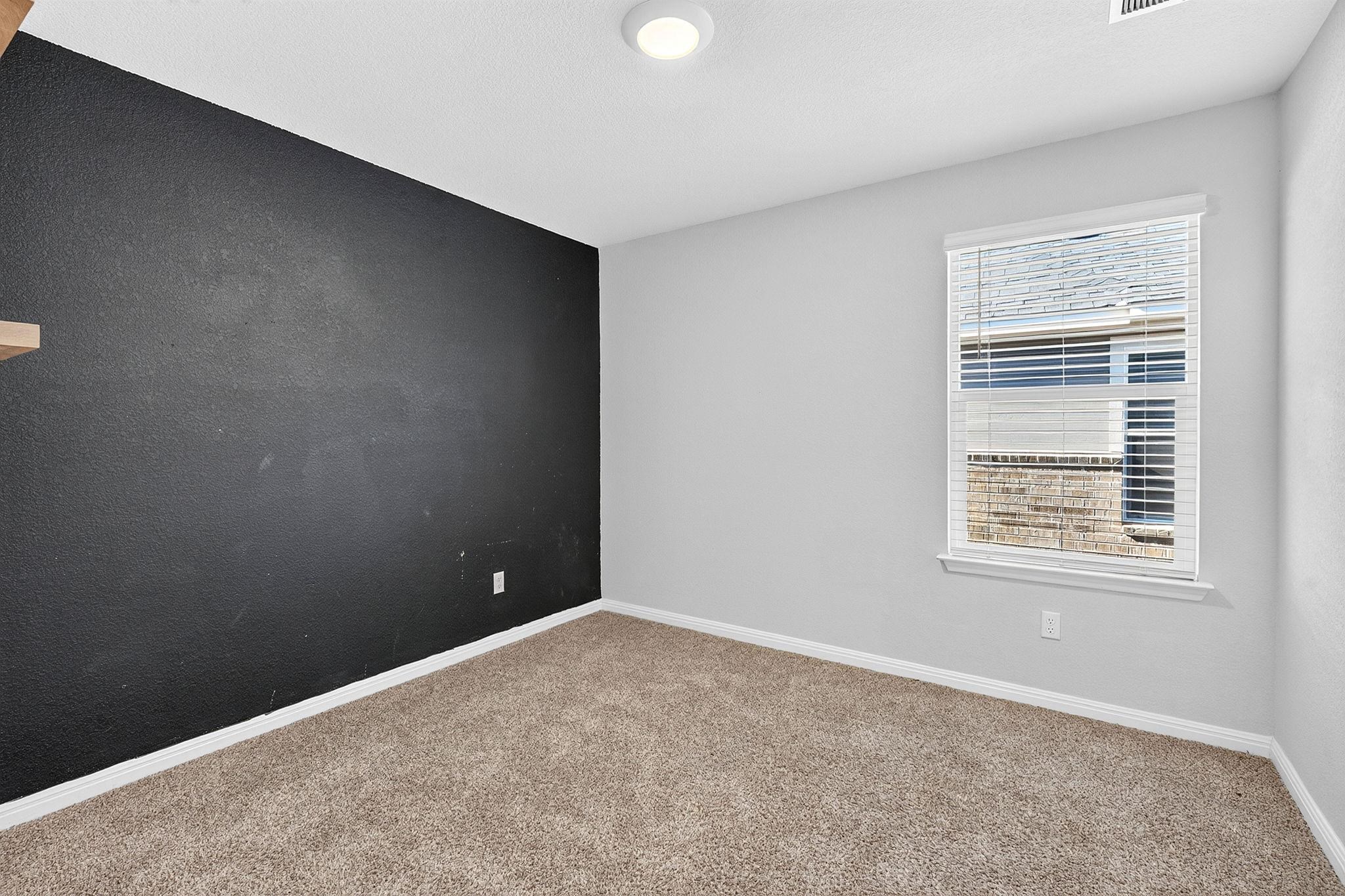 Natural light fills this versatile room featuring soft carpet underfoot.