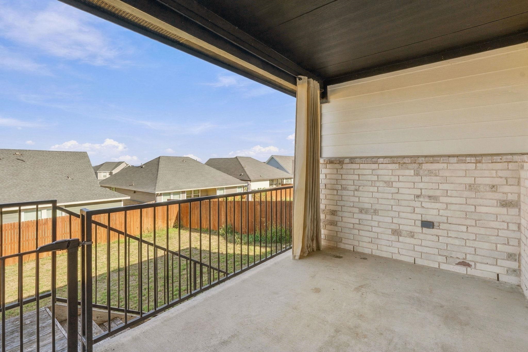 An elevated covered patio features concrete flooring and brick accents overlooking the fenced yard.