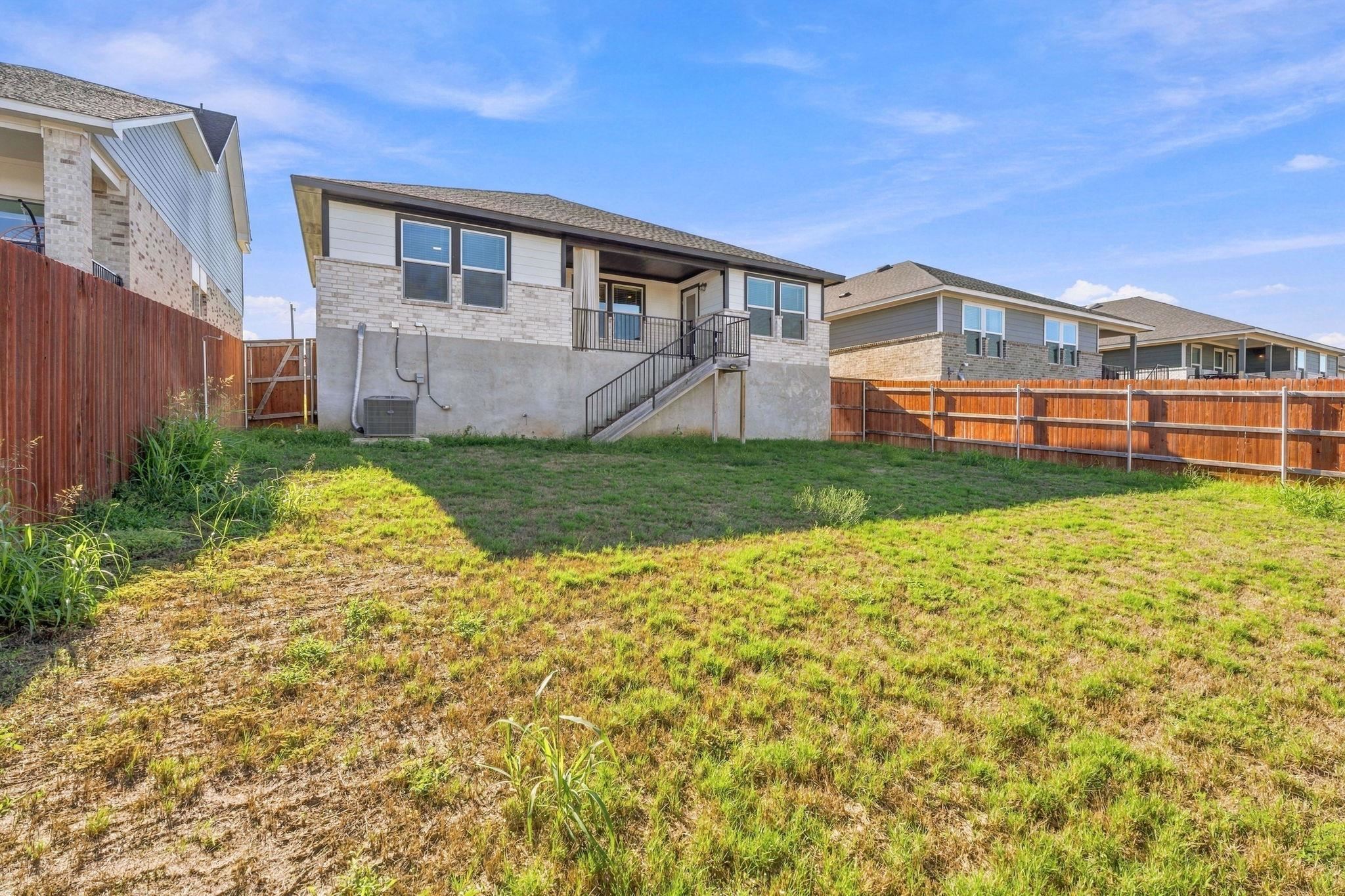An enclosed grassy lawn offers privacy and outdoor potential behind this modern home.