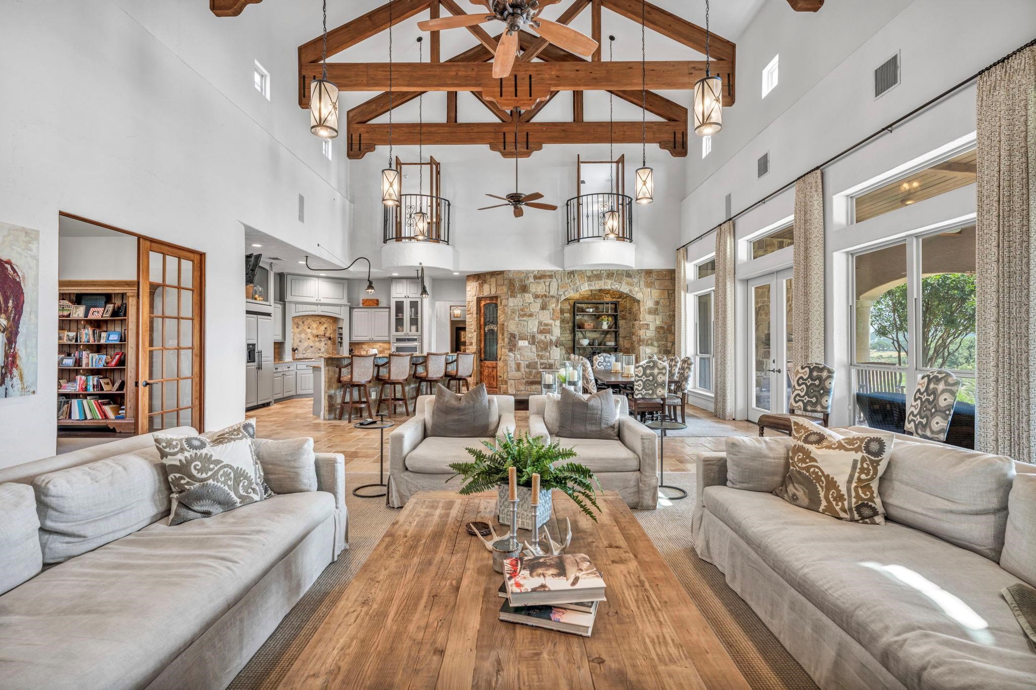 Living area with a ceiling fan, high vaulted ceiling, and beamed ceiling