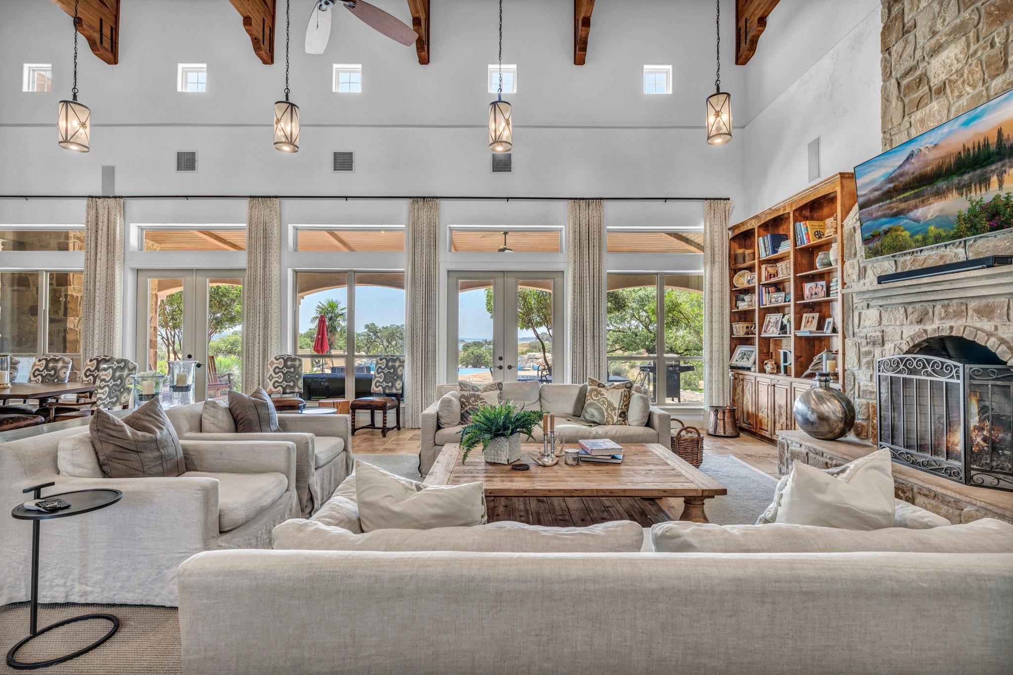Living area w/ french doors, natural lighting, a fireplace, a high/beamed ceiling, built-in bookcase