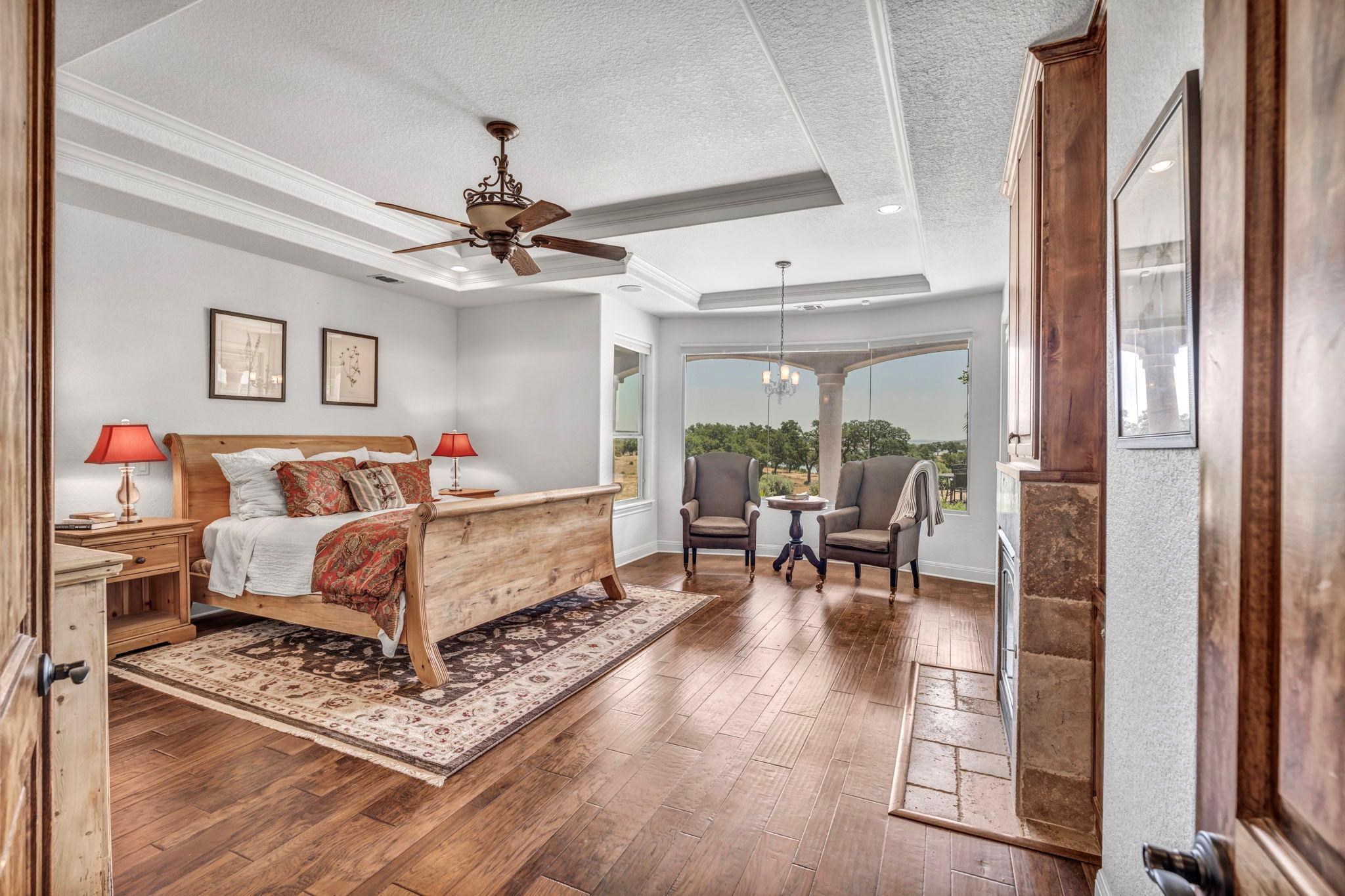 Primary retreat w/ stone-clad fireplace, spa bath & sitting nook overlooking the water