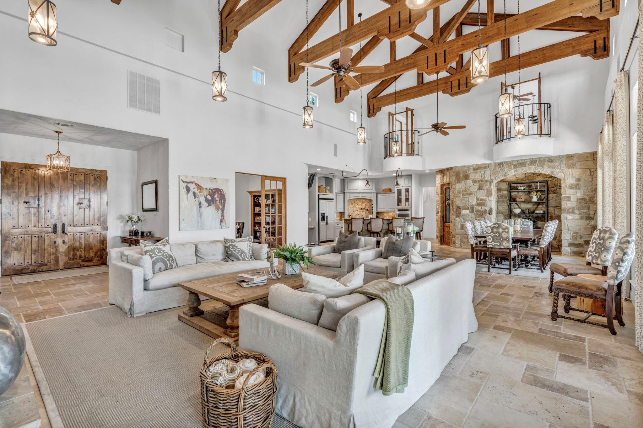 Featuring a chandelier, high vaulted ceiling, stone tile floors, ceiling fan, and beamed ceiling
