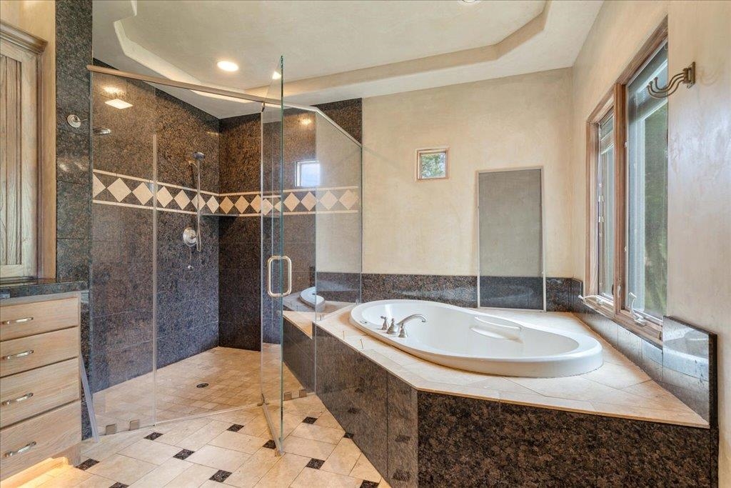 Walk-in shower and jetted tub loacted in primary bathroom