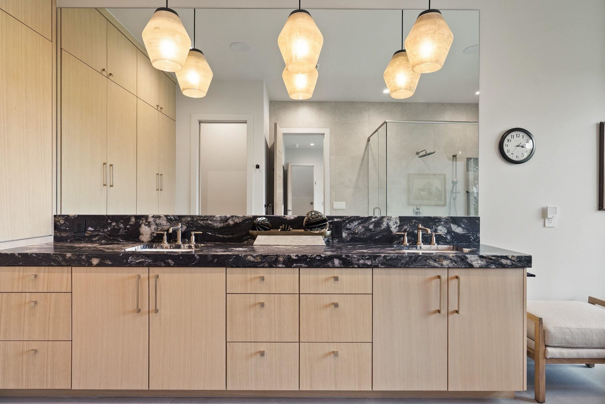 Leathered and honed counter with dual vanities and plenty of storage are located in the primary bath
