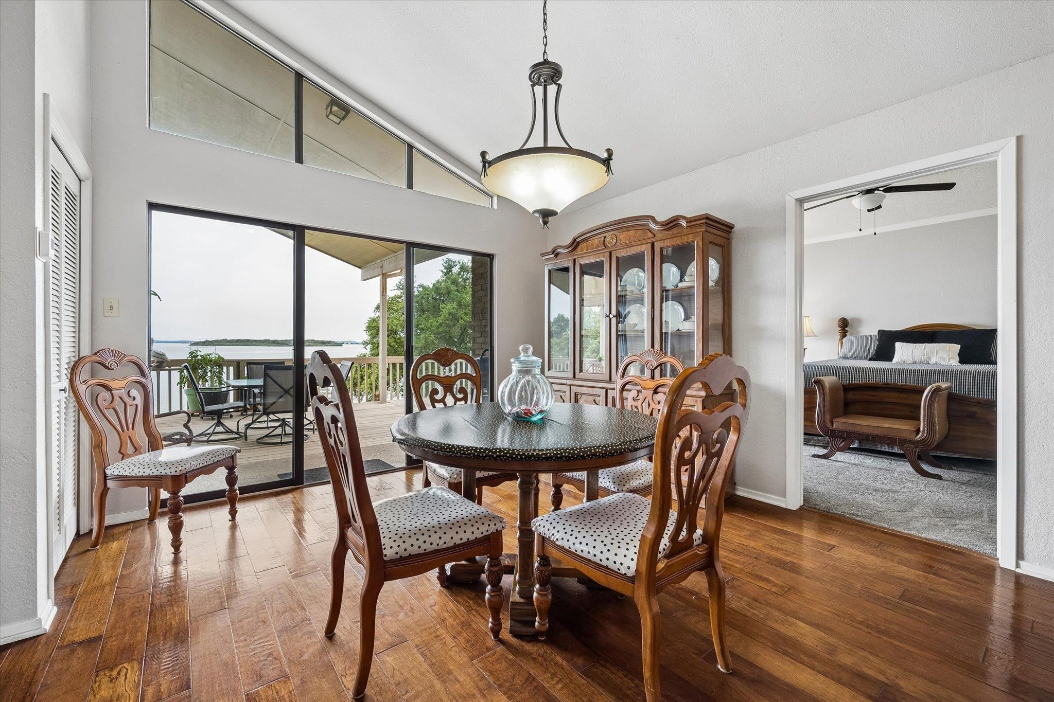 Hardwood floors and a sophisticated dining area extend to a spacious outdoor deck with scenic lake.