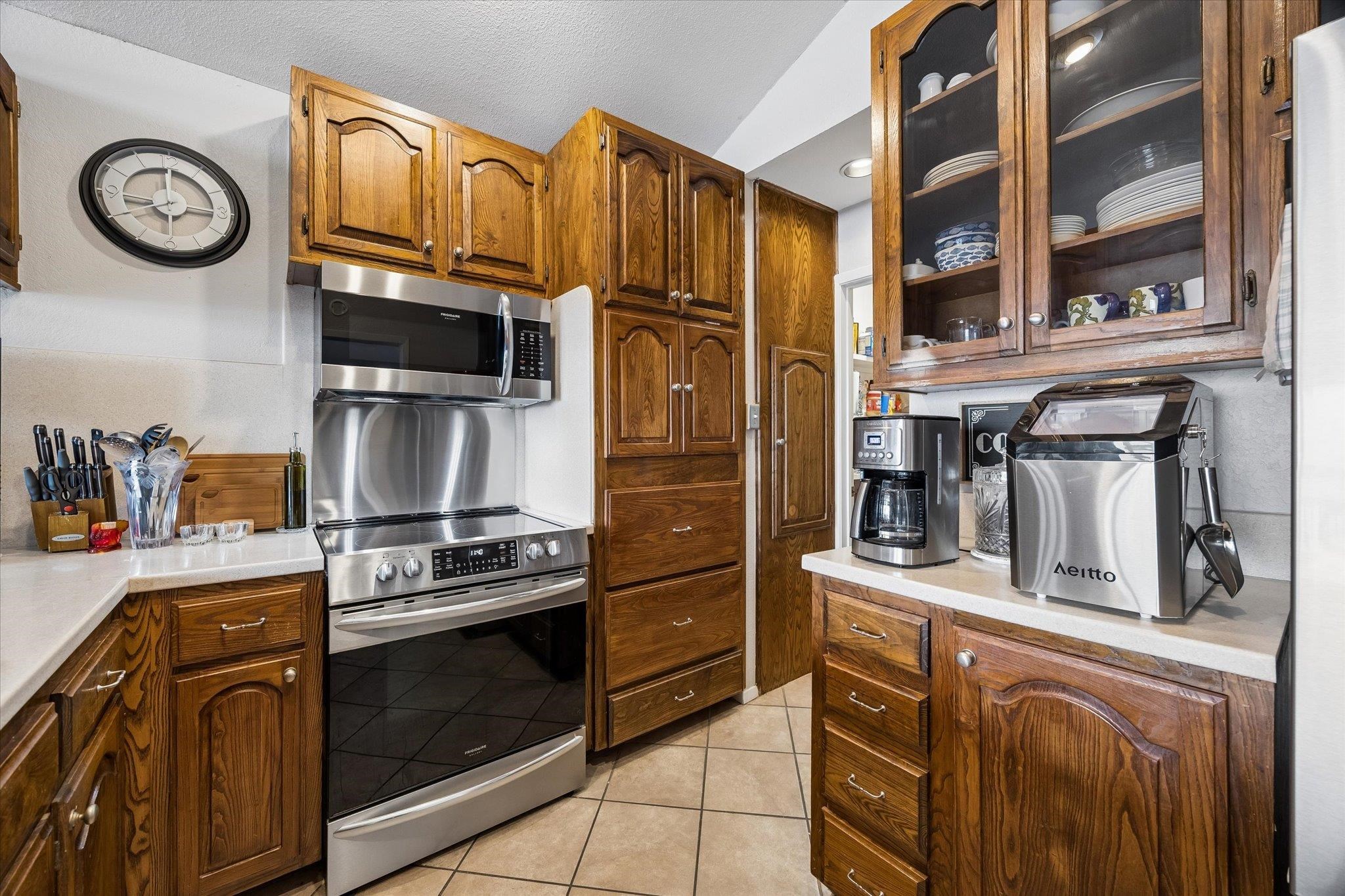 A well-appointed kitchen features rich wood cabinetry and contemporary stainless steel appliances, r