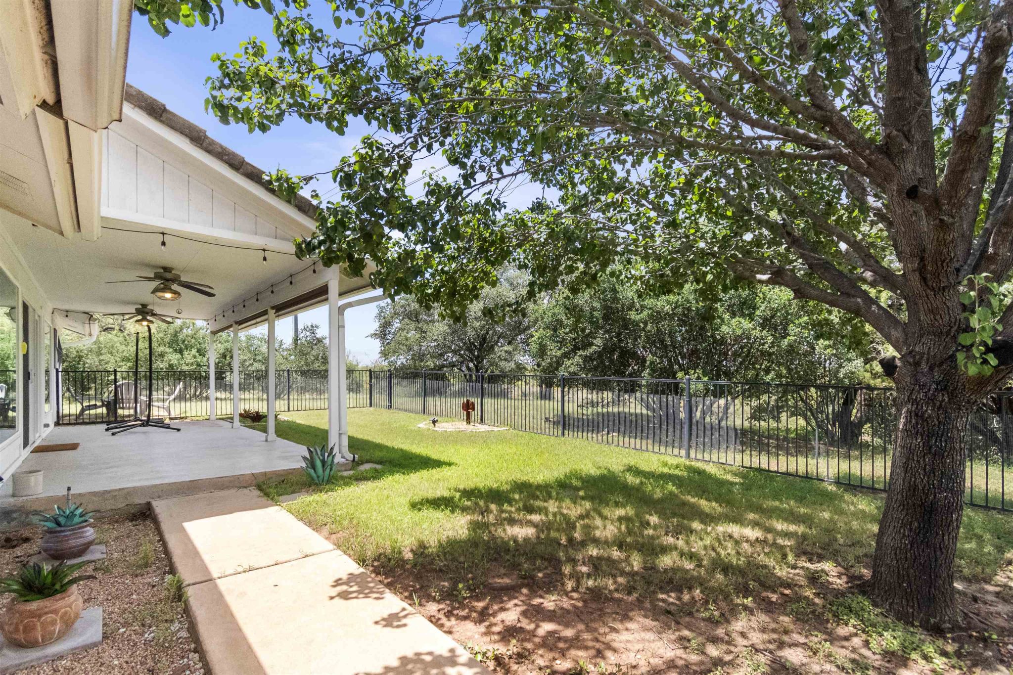 Tranquil covered back patio with mature trees and landscaping