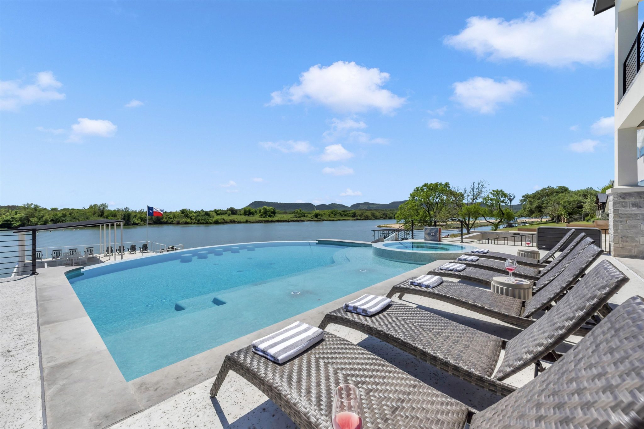 An infinity pool and spa overlook expansive river views from the spacious stone patio.