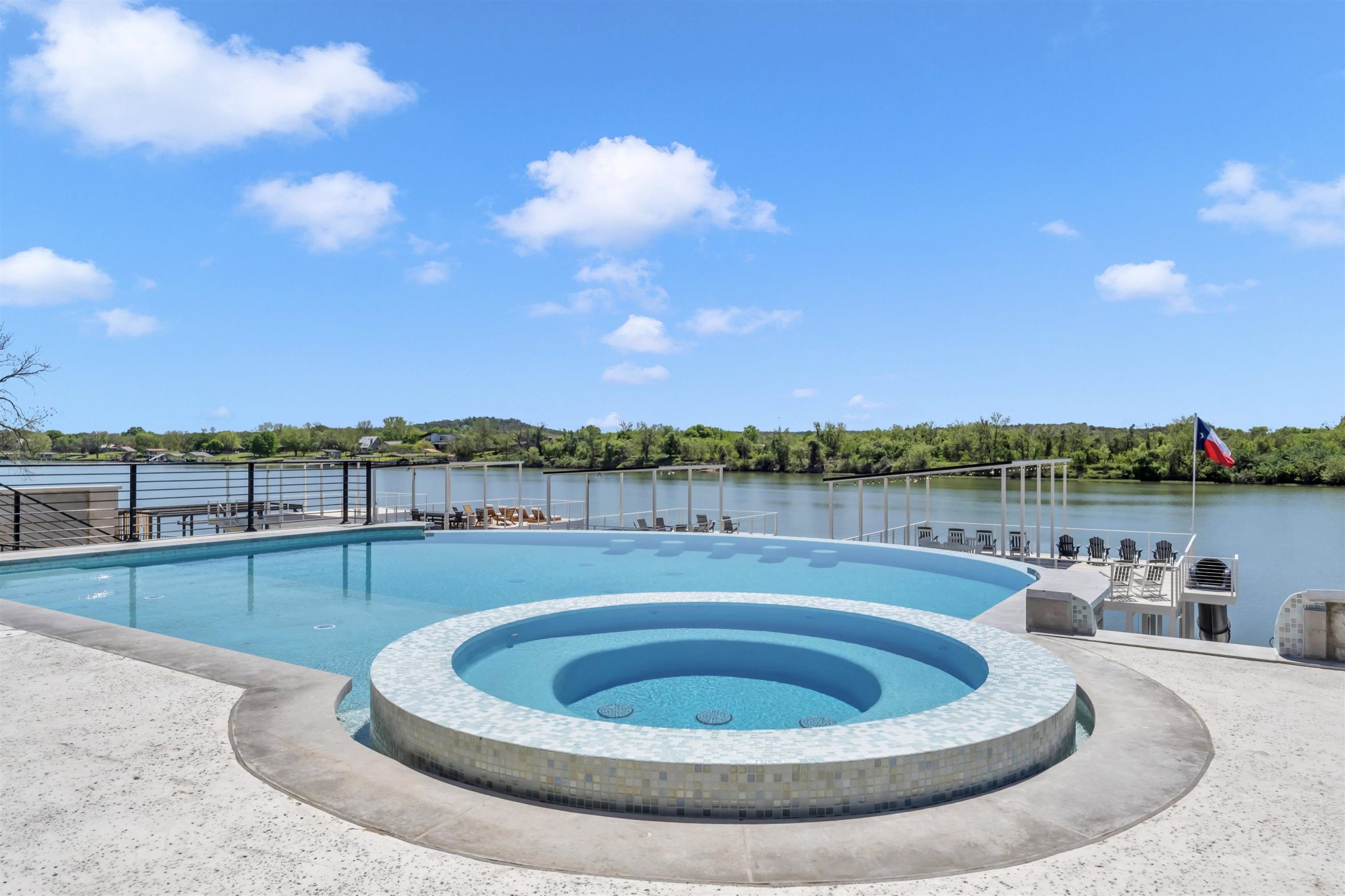 An elevated pool deck overlooks the serene waterfront on a clear day.