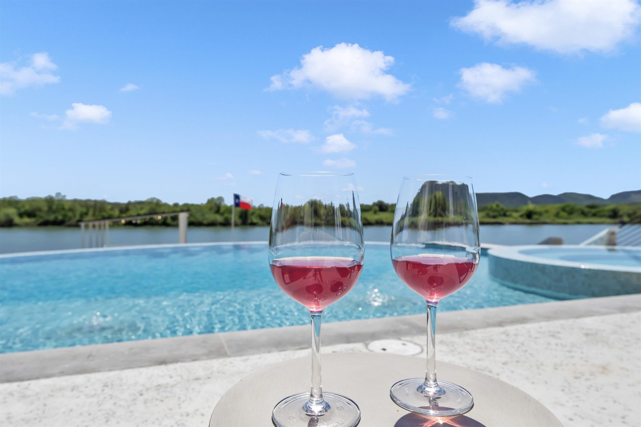 An inviting pool overlooks serene waters and rolling hillsides beyond.