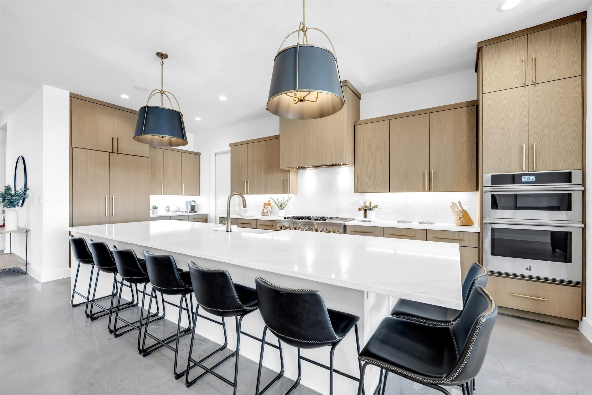 Sleek flat-panel wood cabinetry and a massive quartz island define this contemporary culinary space.