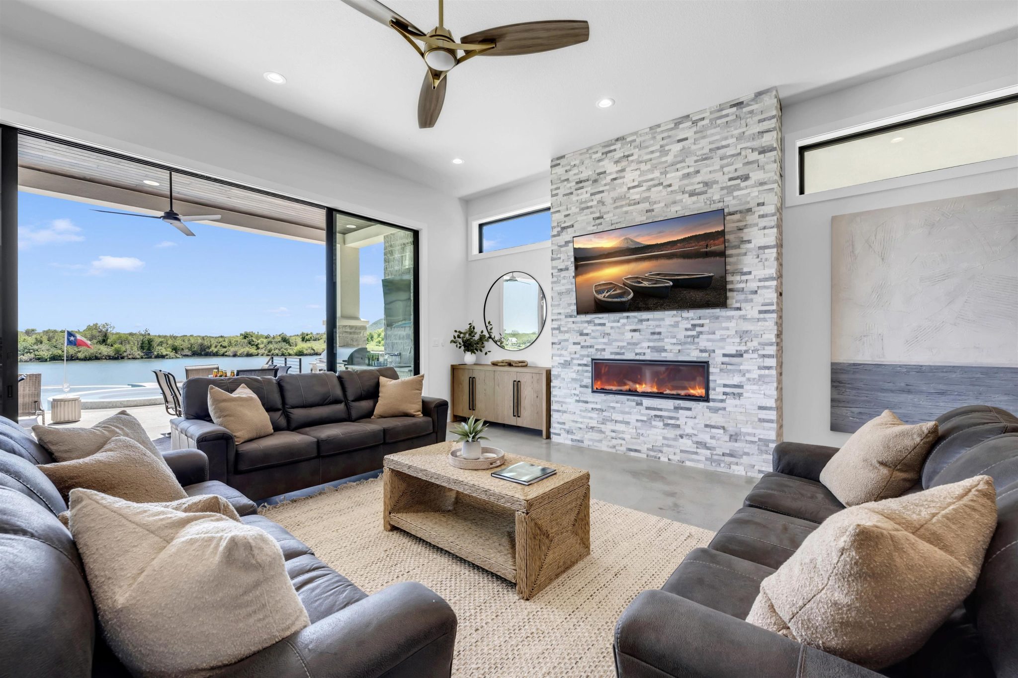 Living room one: A stone fireplace anchors the living room beside sliding glass doors revealing wate
