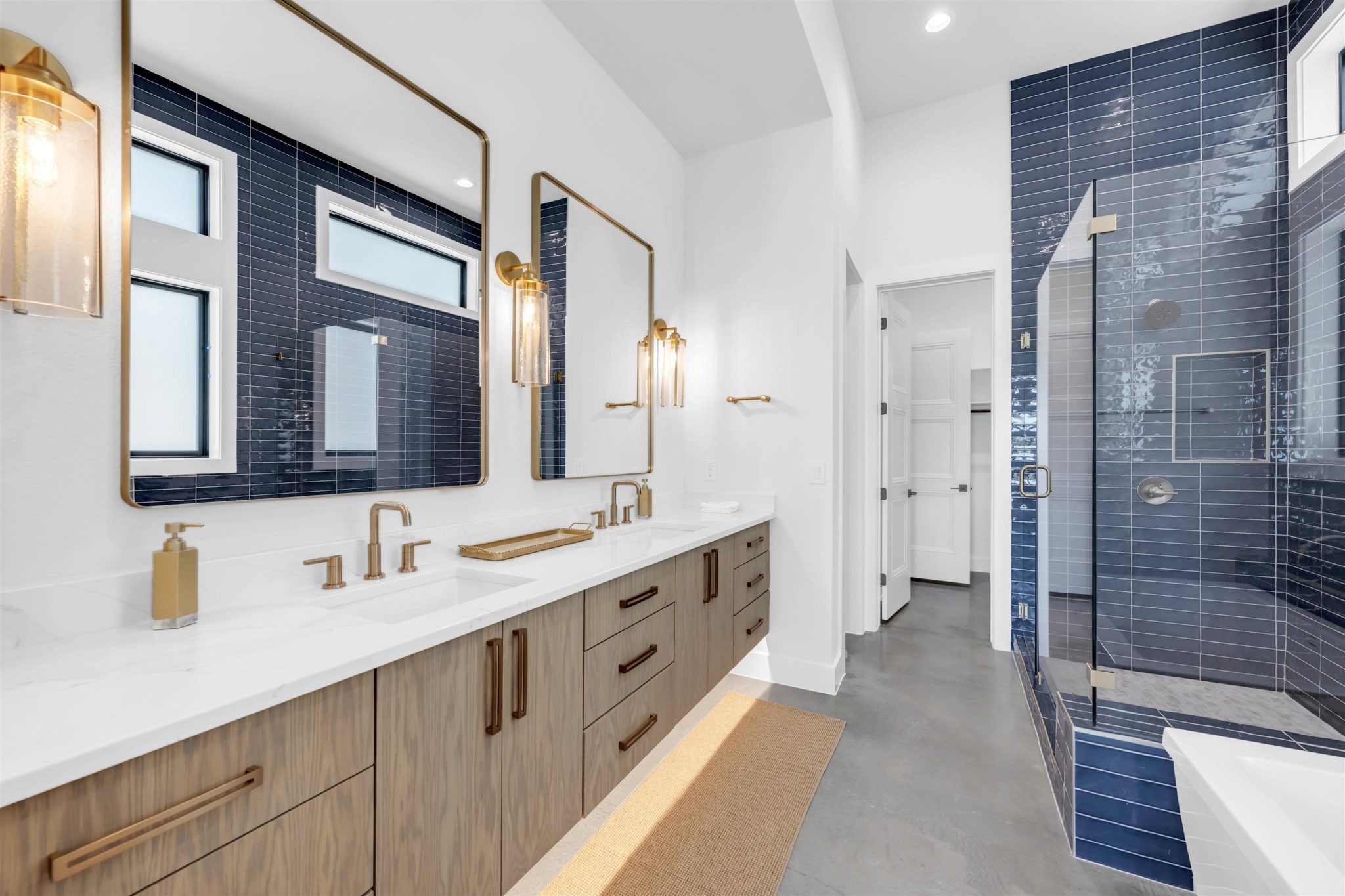 Primary bathroom. Gleaming stone counters pair with a walk-in tiled shower in this modern washroom.