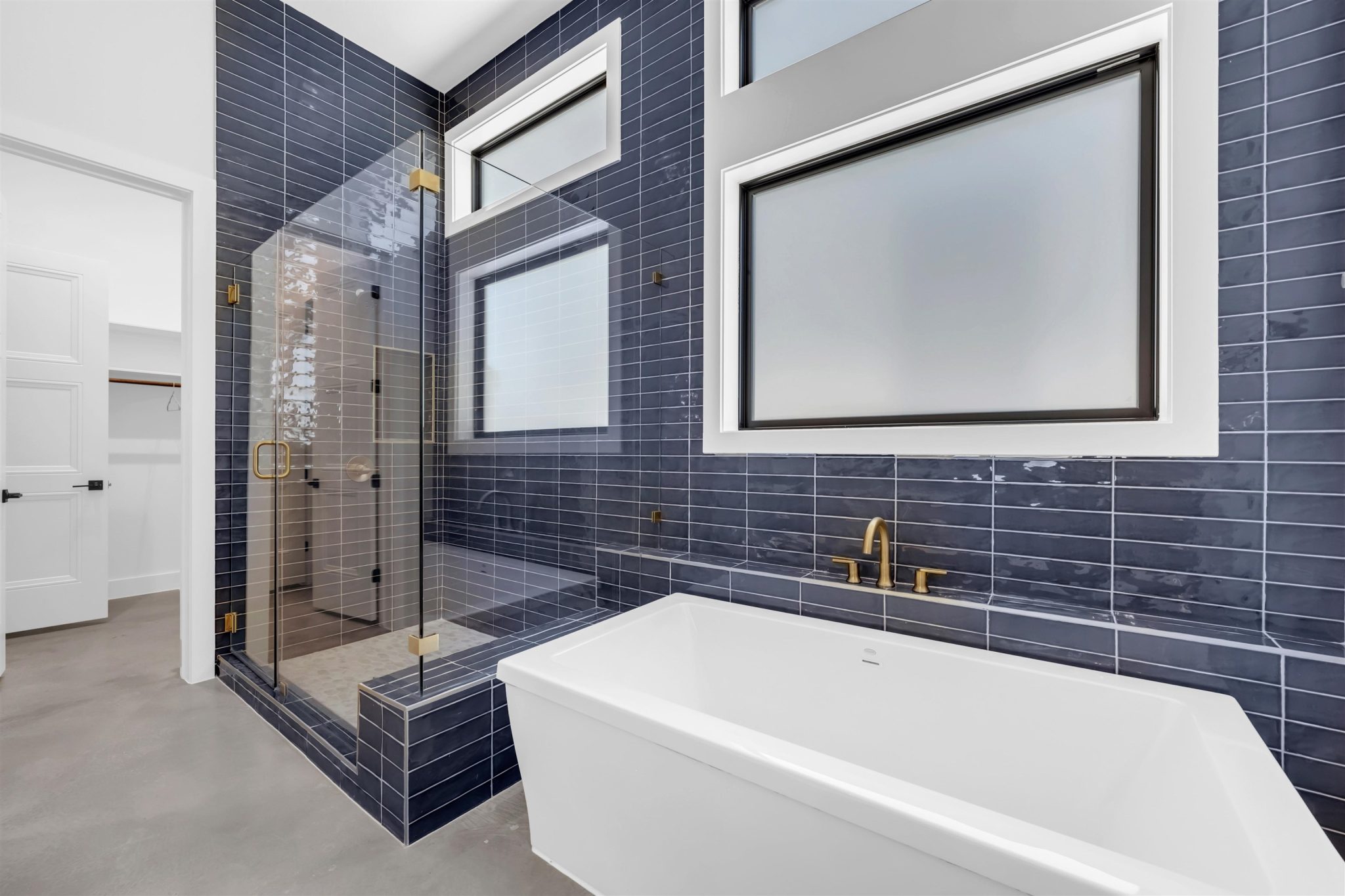 Bold tile surrounds a freestanding soaking tub and a spacious glass-enclosed shower.