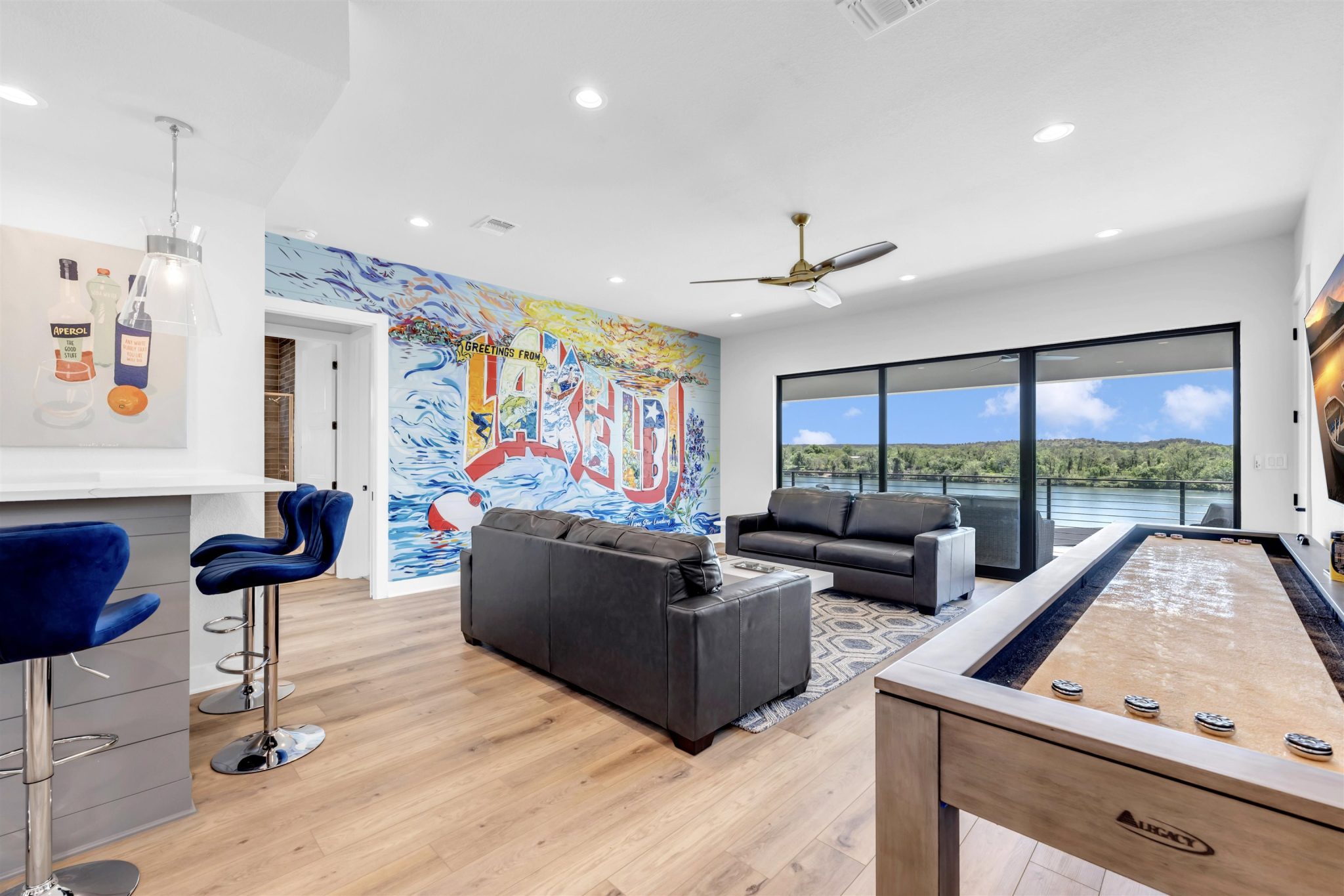 Living room two: Wood floors and floor-to-ceiling glass doors frame tranquil waterfront