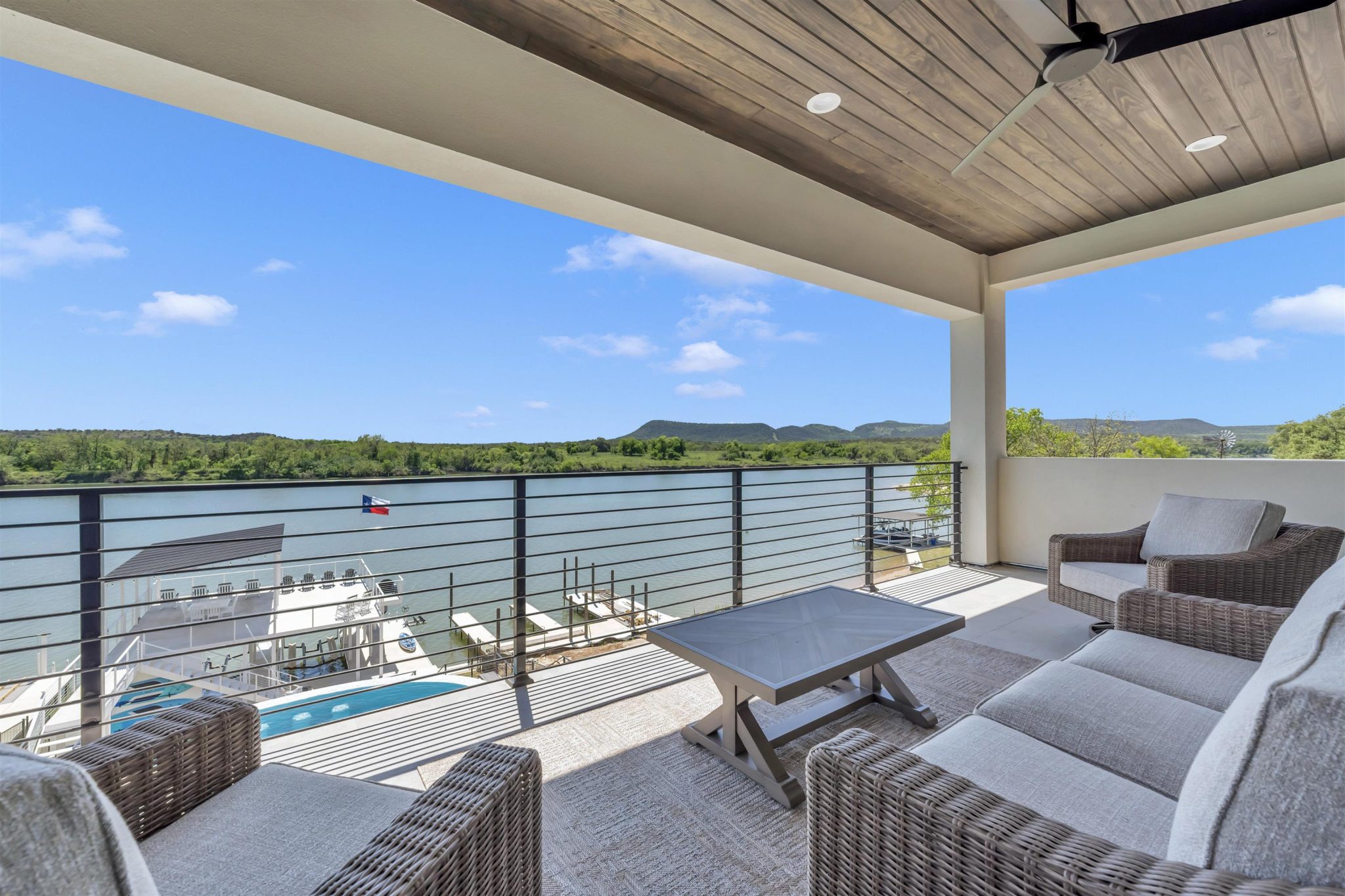 A spacious covered balcony overlooks the calm river and rolling hills beyond.
