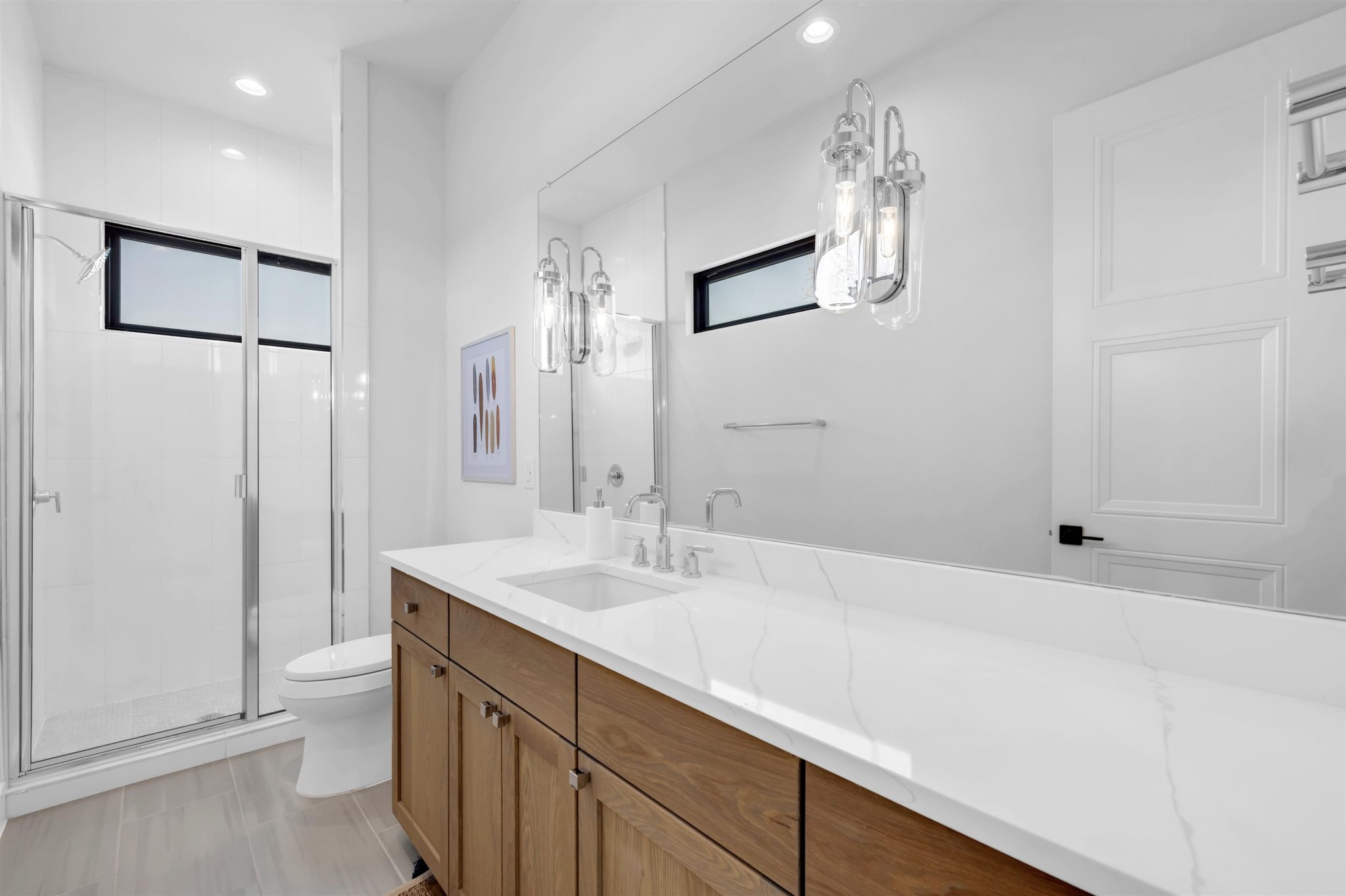 Bathroom four: Gleaming stone countertops and a spacious glass shower elevate this modern bathroom.