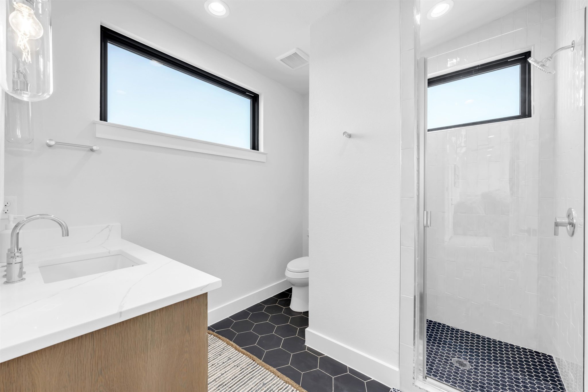 Bathroom seven: A modern bathroom features a glass-enclosed shower, stone-look vanity.