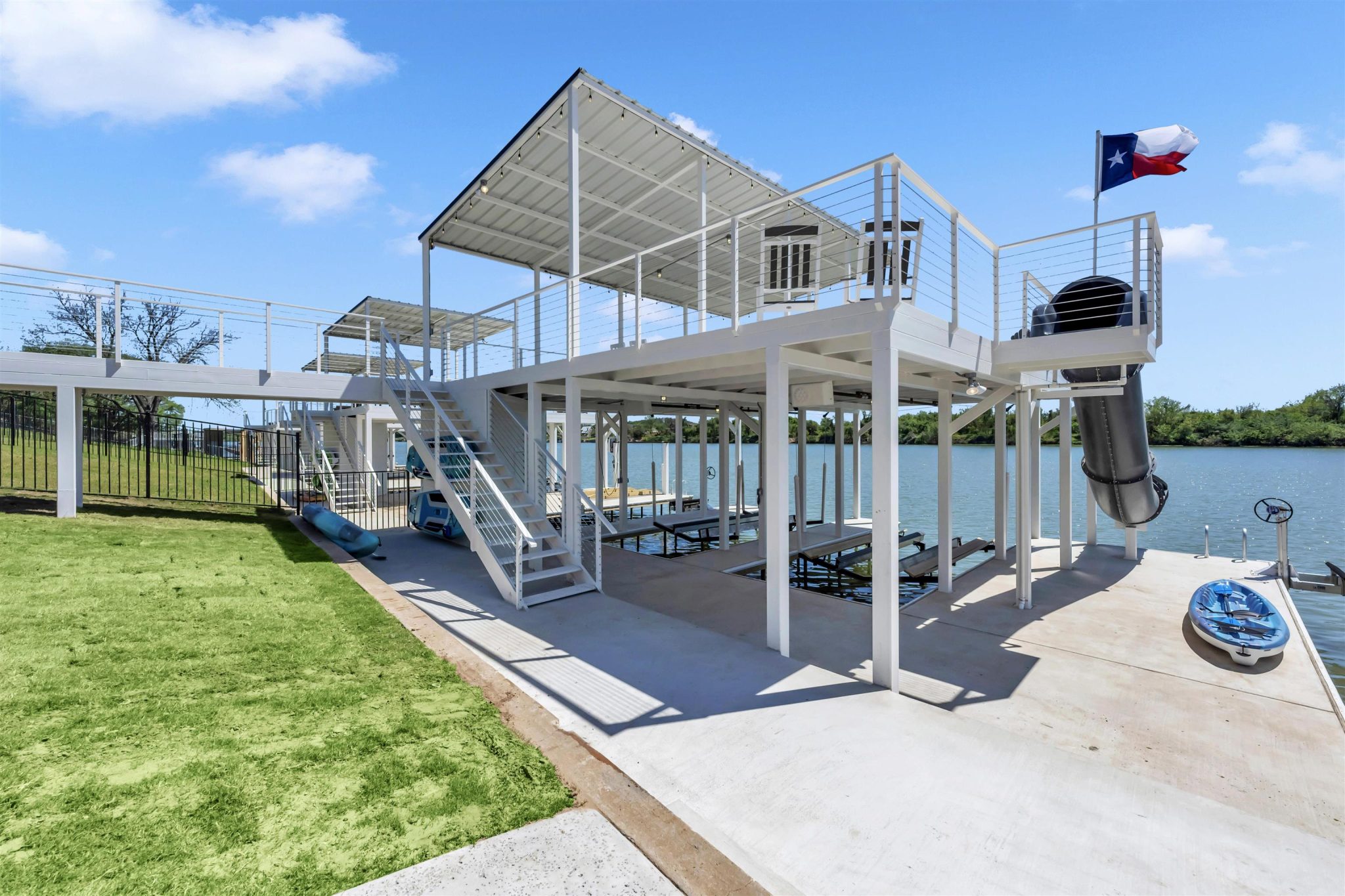 A multi-level boat dock with a covered upper deck overlooks the calm water.