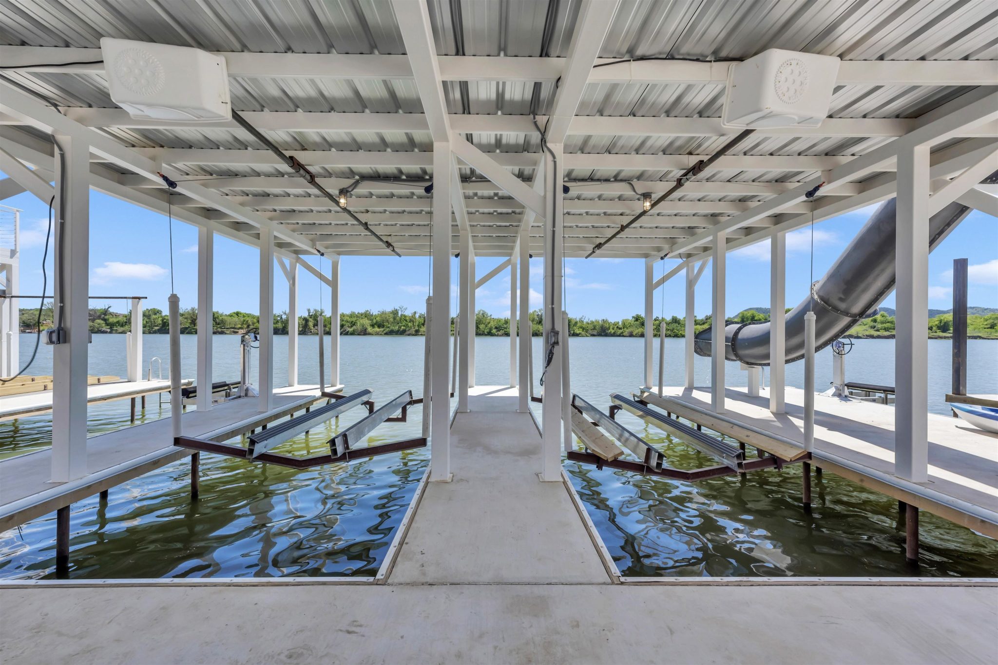 Double boat slips with mechanical lifts sit securely covered beneath a metal canopy.