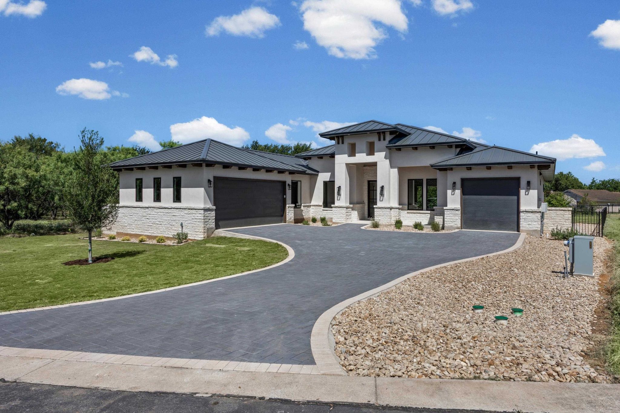 A grand paved driveway gracefully leads to a contemporary residence with dual garages