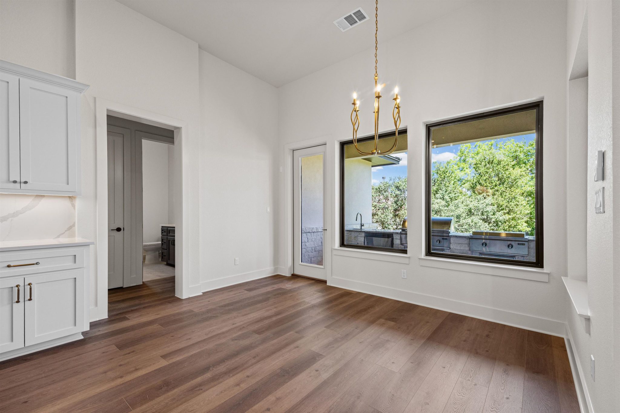 Open-concept dining area with high ceilings and a view of the outdoor kitchen