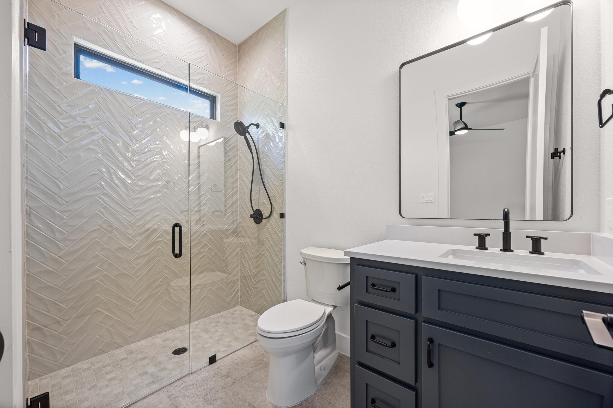 Well-lit secondary bath features a glass-enclosed shower and modern fixtures.