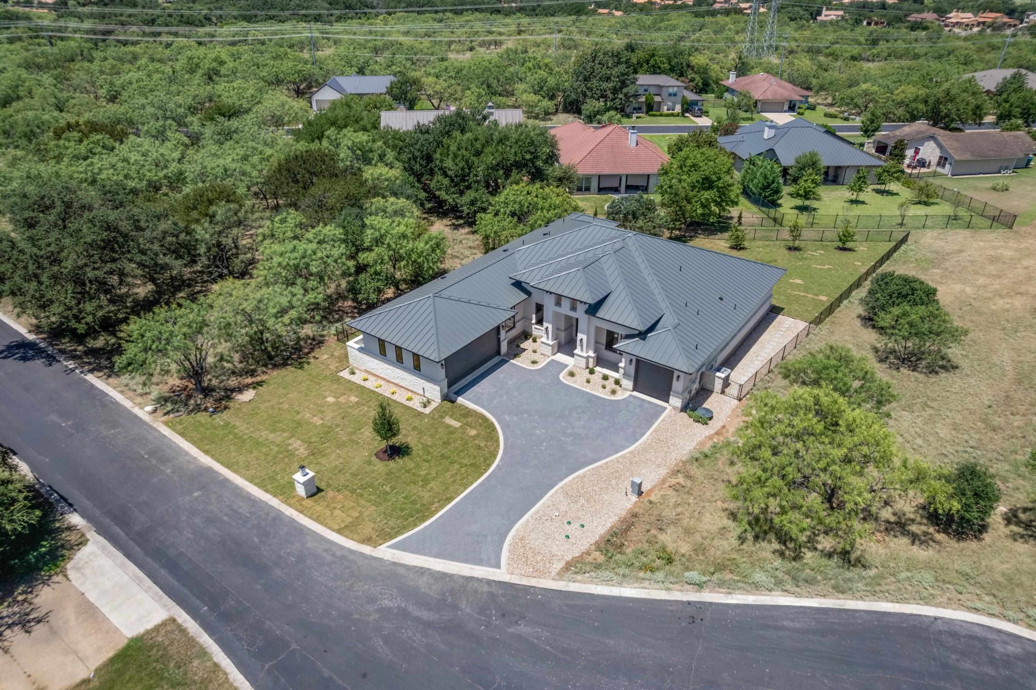 Aerial perspective reveals a contemporary residence with a metal roof and an elegantly paved drive