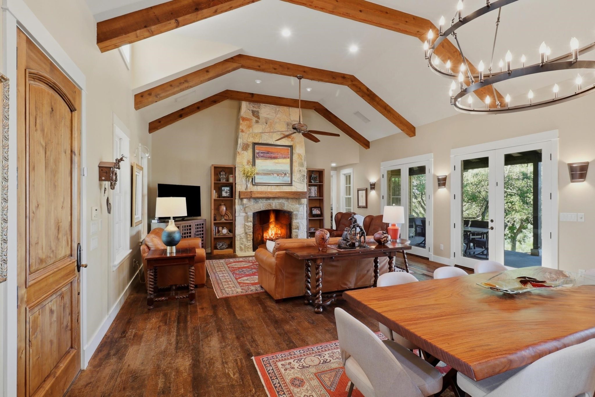 Impressive Great Room with soaring ceiling, dramatic double-tiered chandelier, stone fireplace.