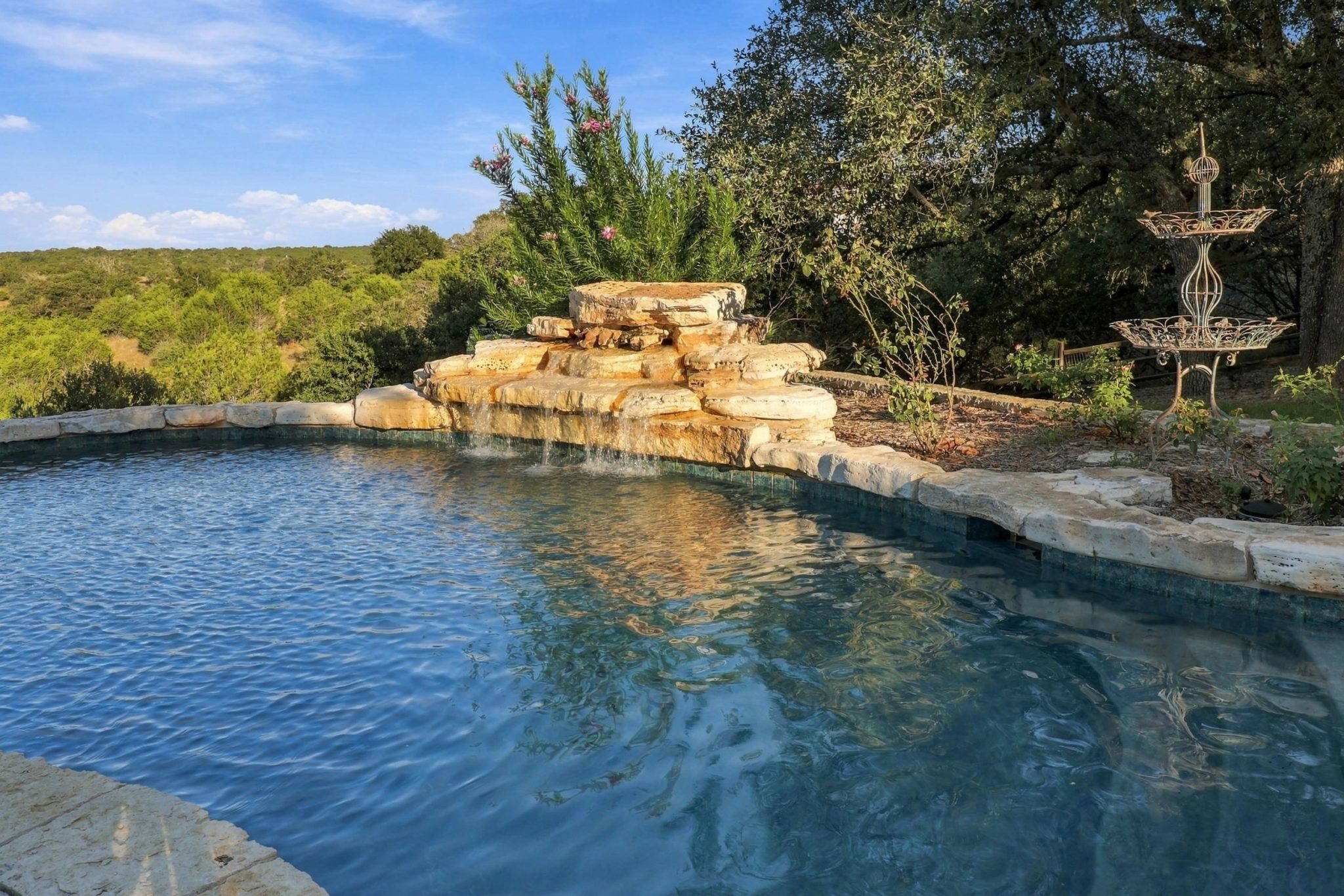 Poolside living surrounded by native landscaping and peaceful Hill Country scenery.