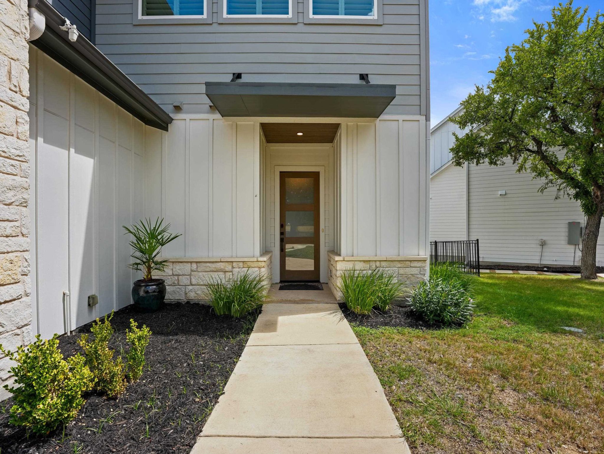 A concrete walkway leads directly to the covered glass front entry of this modern residence.
