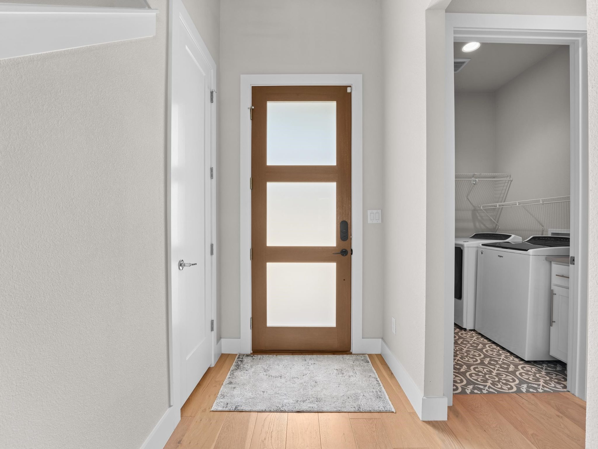 A modern glass-paneled entryway door coordinates beautifully with warm hardwood flooring.