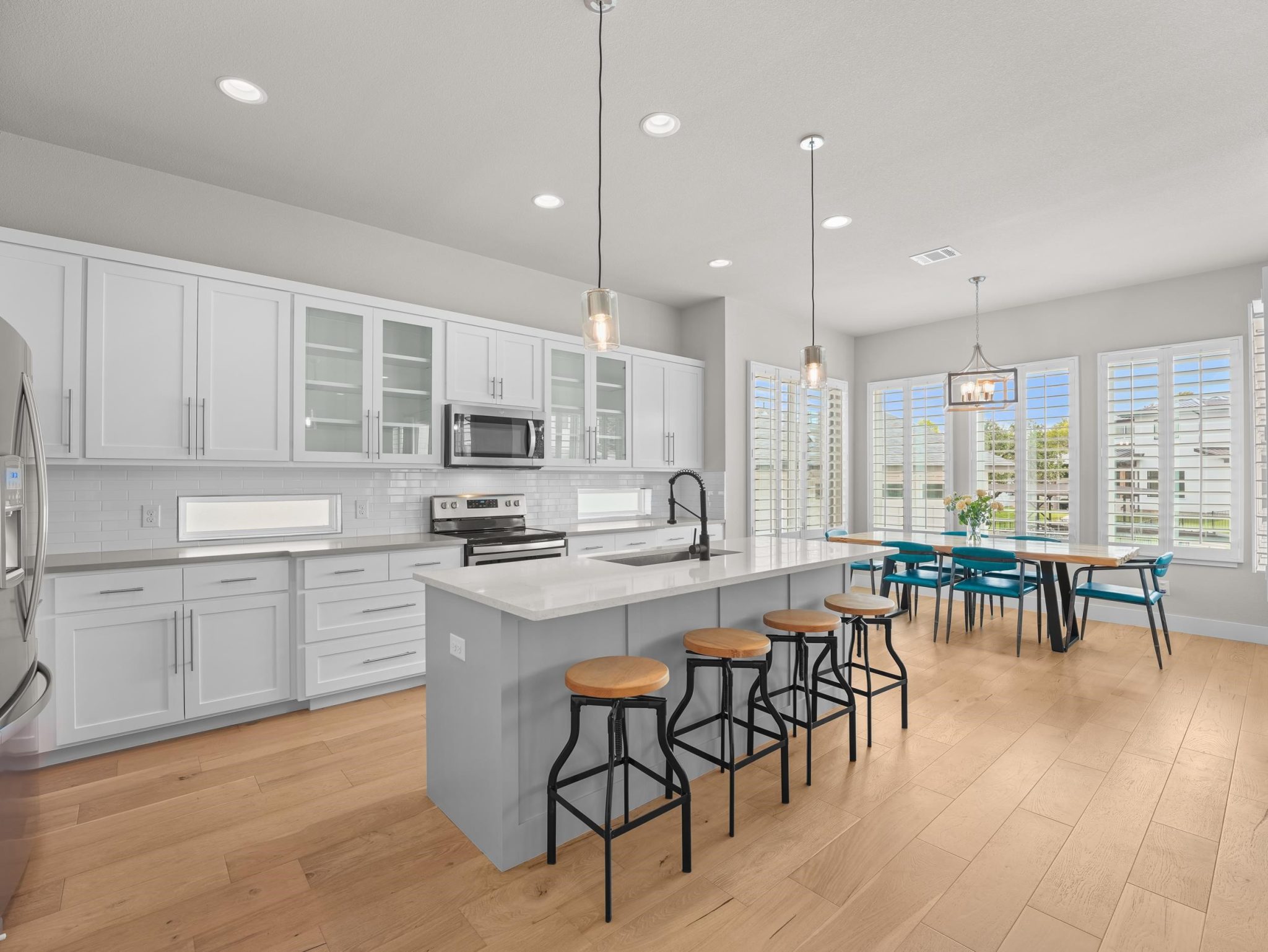 Rich hardwood flooring complements clean white cabinetry and a central island in this culinary space