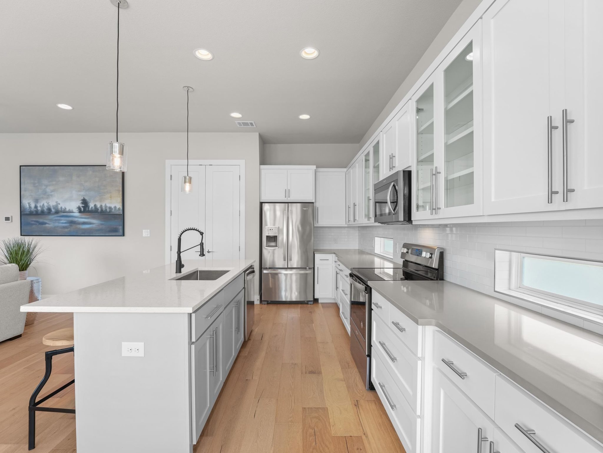 Gleaming hardwood floors and stone counters elevate this modern kitchen with high ceilings.