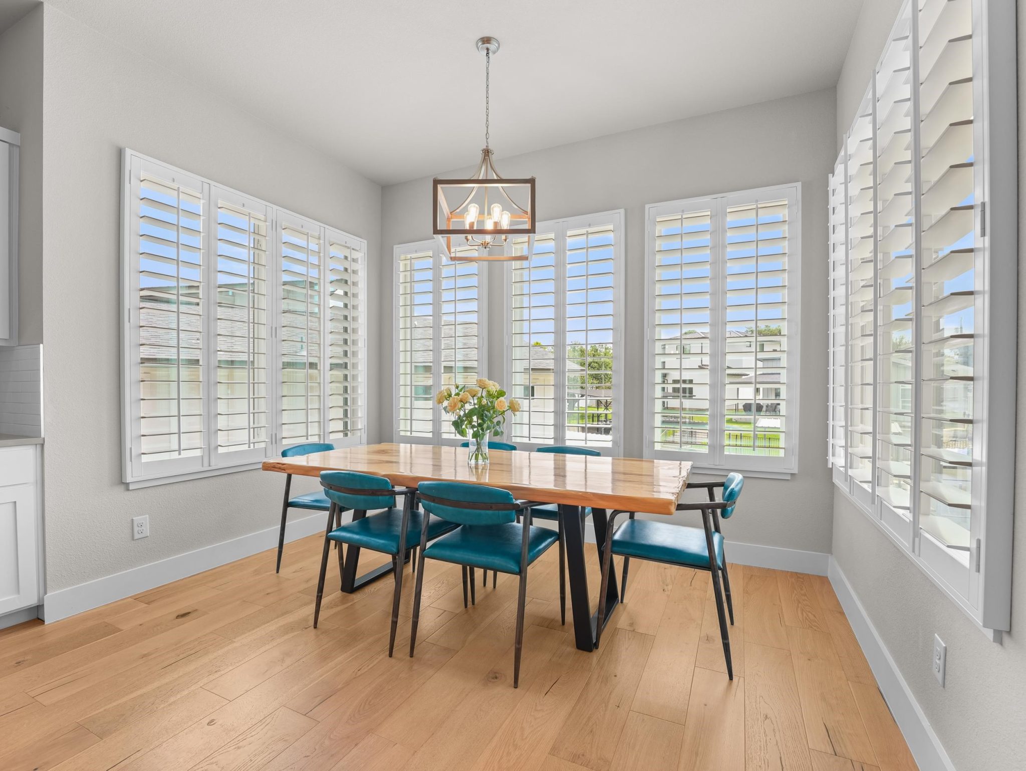 Warm wood floors and multiple shuttered windows frame this welcoming dining area.