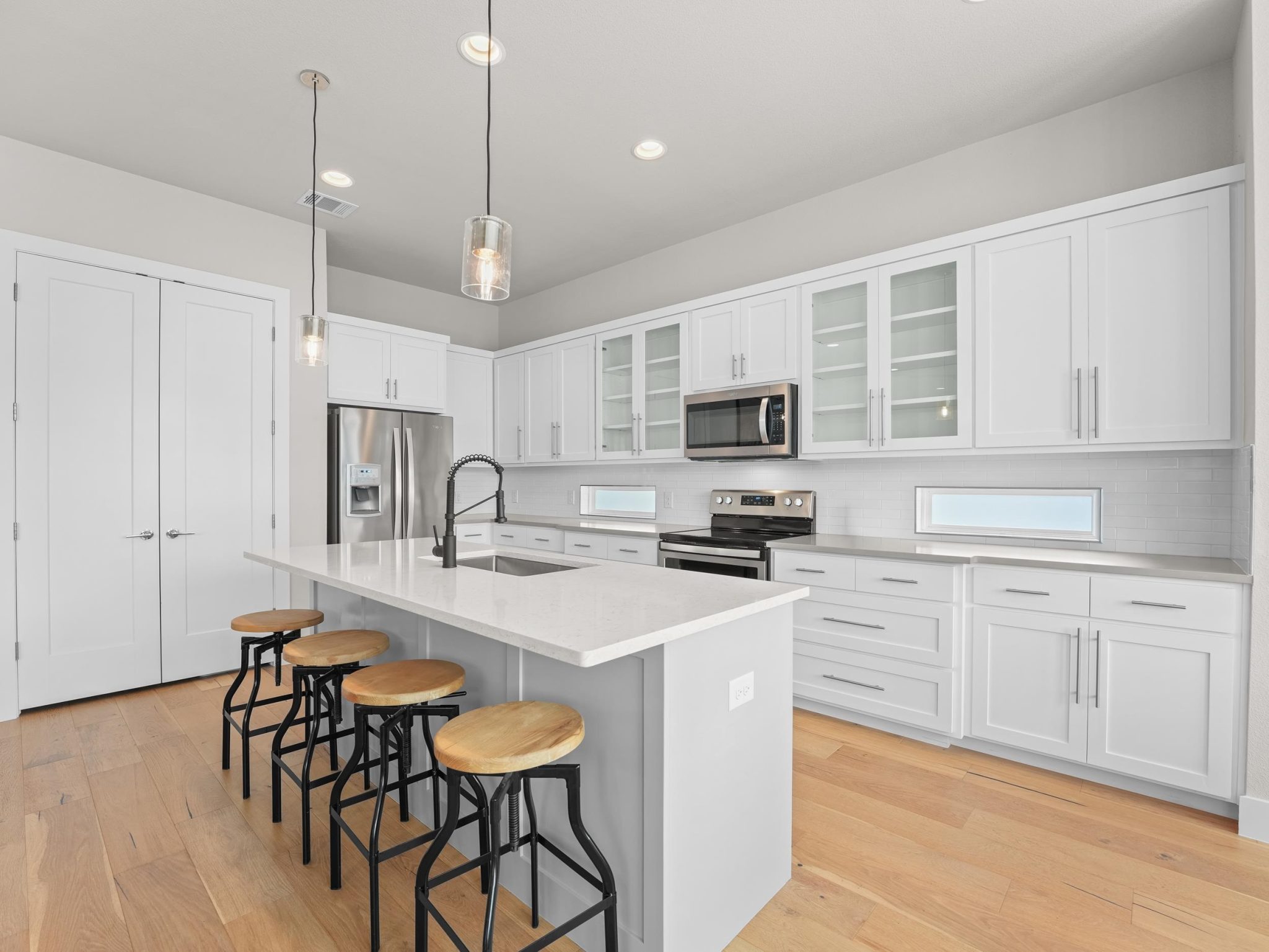 Streamlined cabinetry and quartz surfaces highlight this open culinary space.