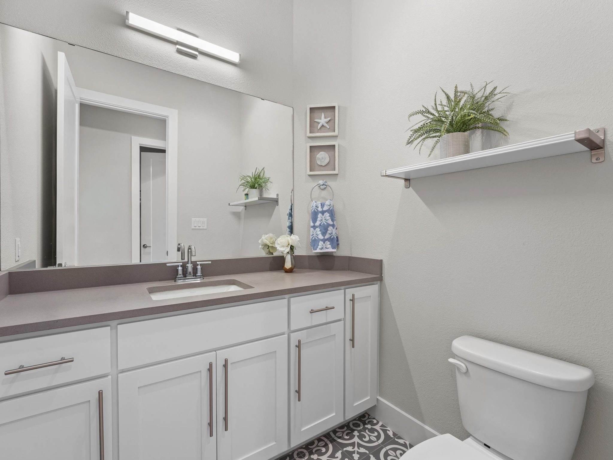 A spacious vanity matches the custom tiled flooring in this modern bathroom on first floor.