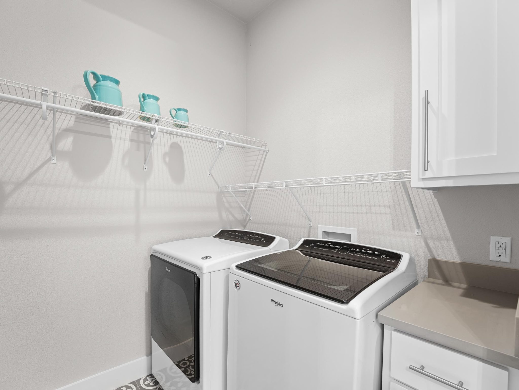 A functional utility space highlights overhead wire shelving and patterned floor tile on the first f