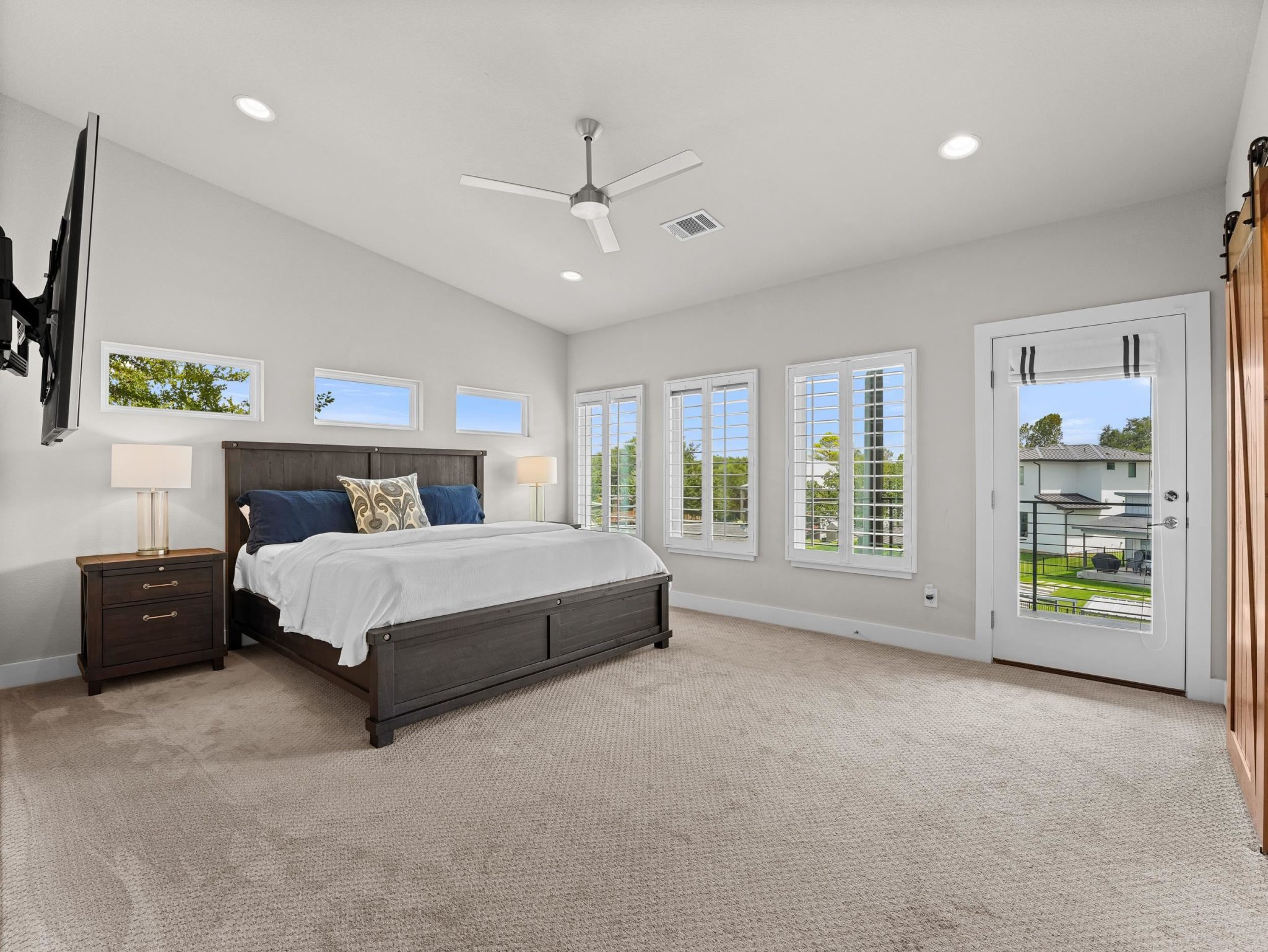 High ceilings and tall windows elevate this carpeted bedroom leading to a private balcony.